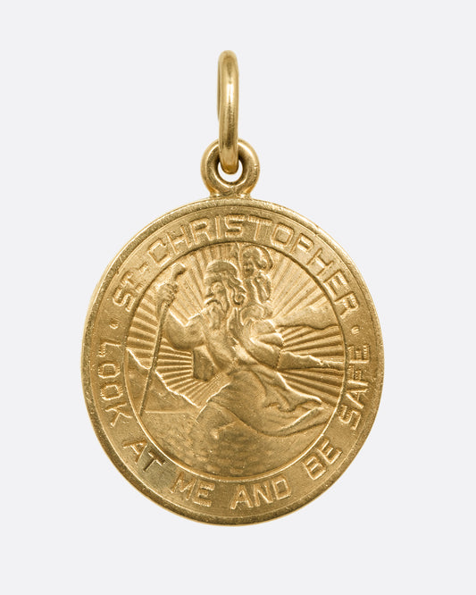 A yellow gold St. Christopher, medallion locket with 'Look at me and be safe' engraved on its edge with a photo frame and a secret slot for a memento on its interior. Shown from the front.