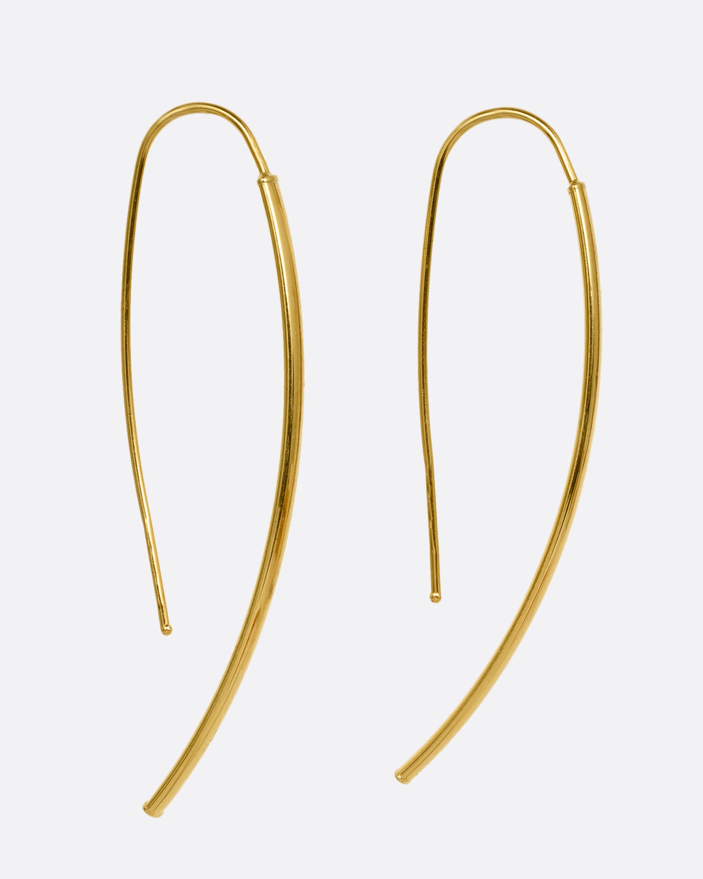 A pair of yellow gold threader half hoop earrings shown from the side.