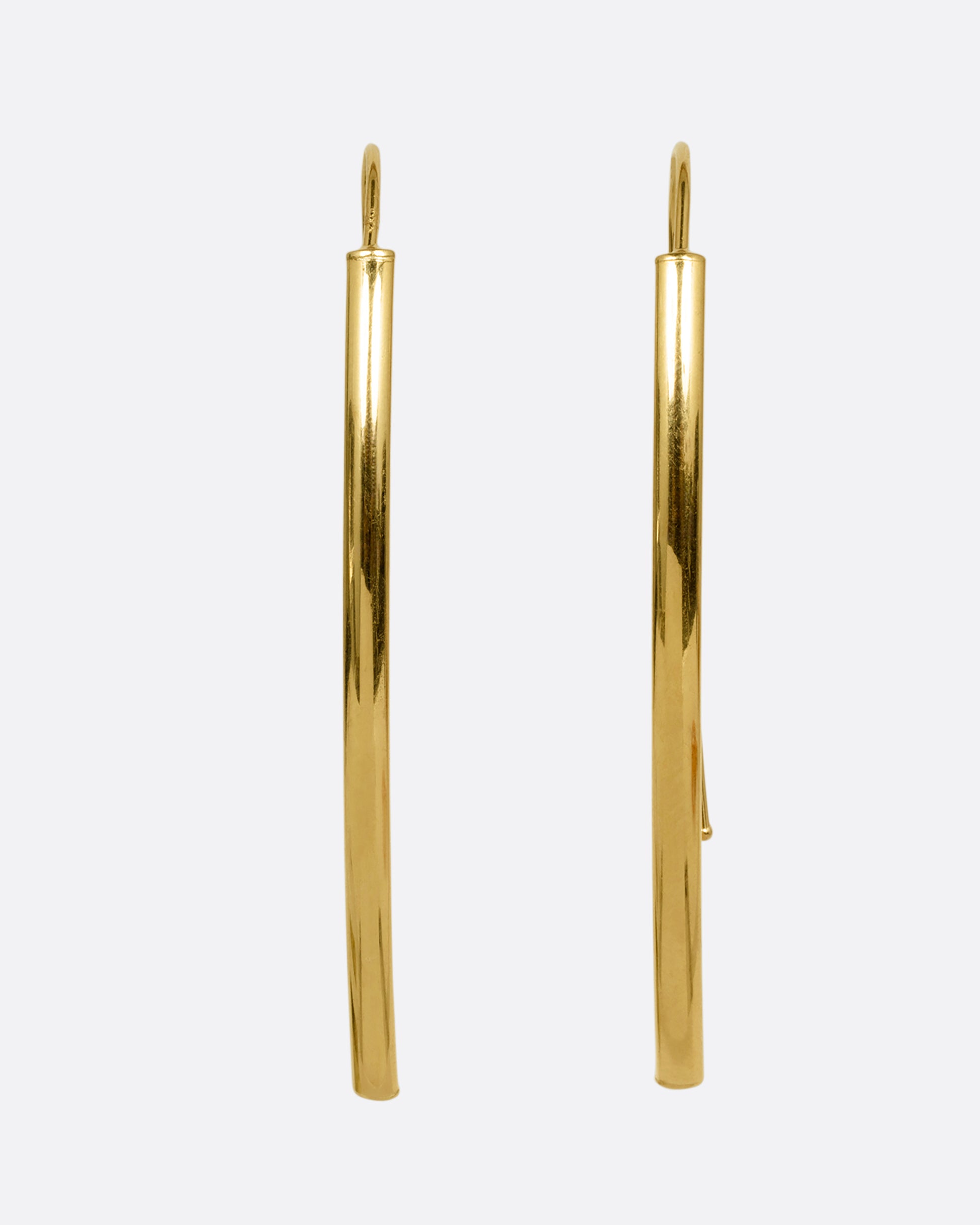 A pair of yellow gold threader half hoop earrings shown from the front.