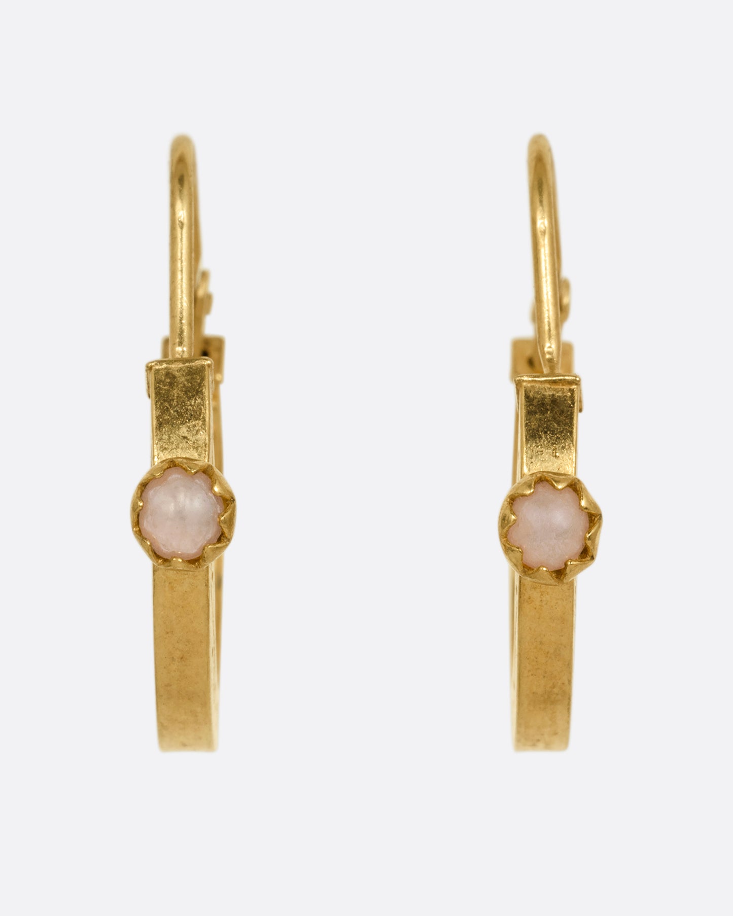 A pair of yellow gold hoop earrings, each with a pearl, shown from the front.