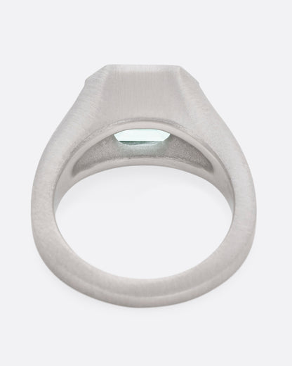 A platinum signet ring with an emerald, shown from the back.