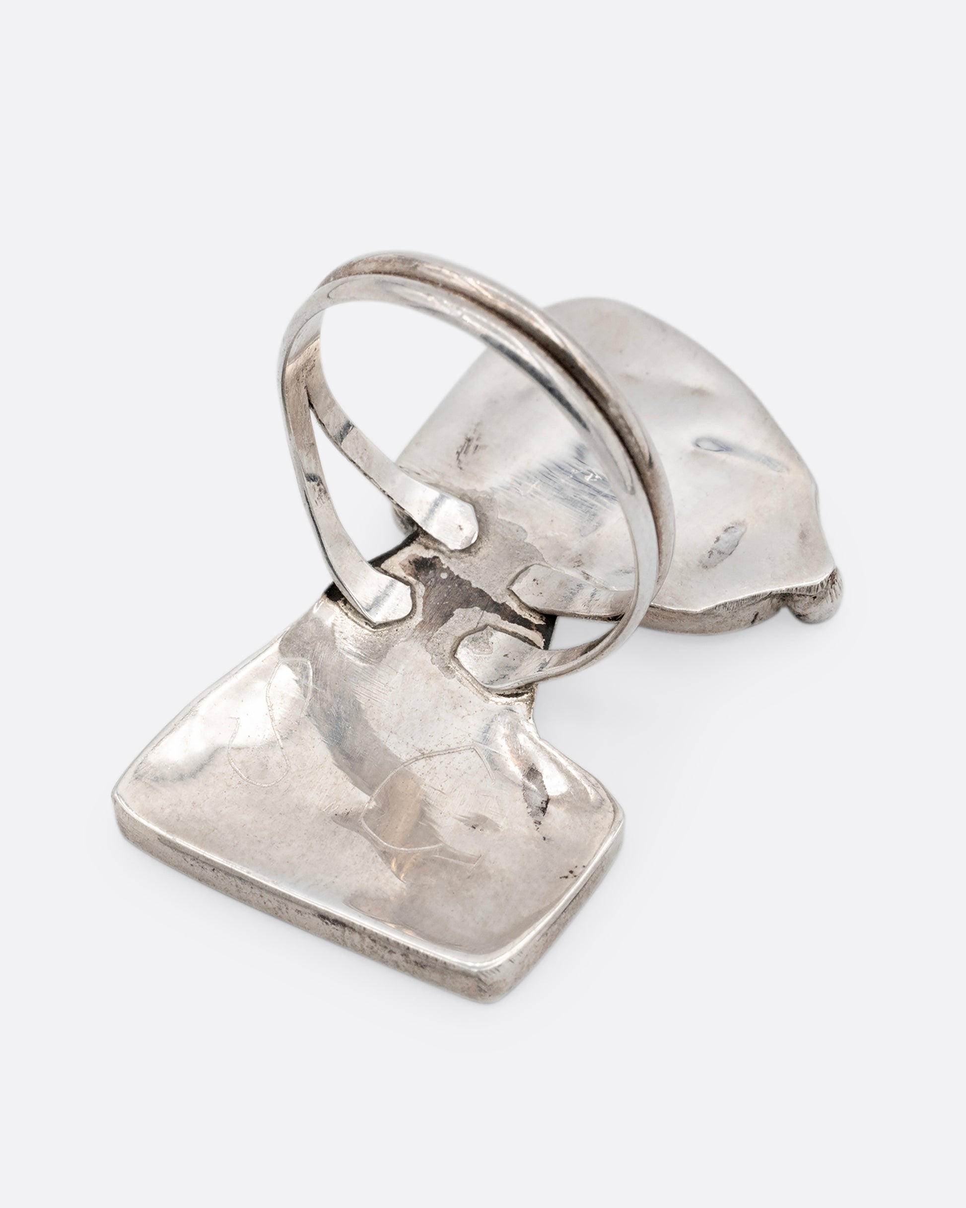 A silver Zunitoon style Snoopy ring made of iridescent mother of pearl and coral inlay. Shown from the back.