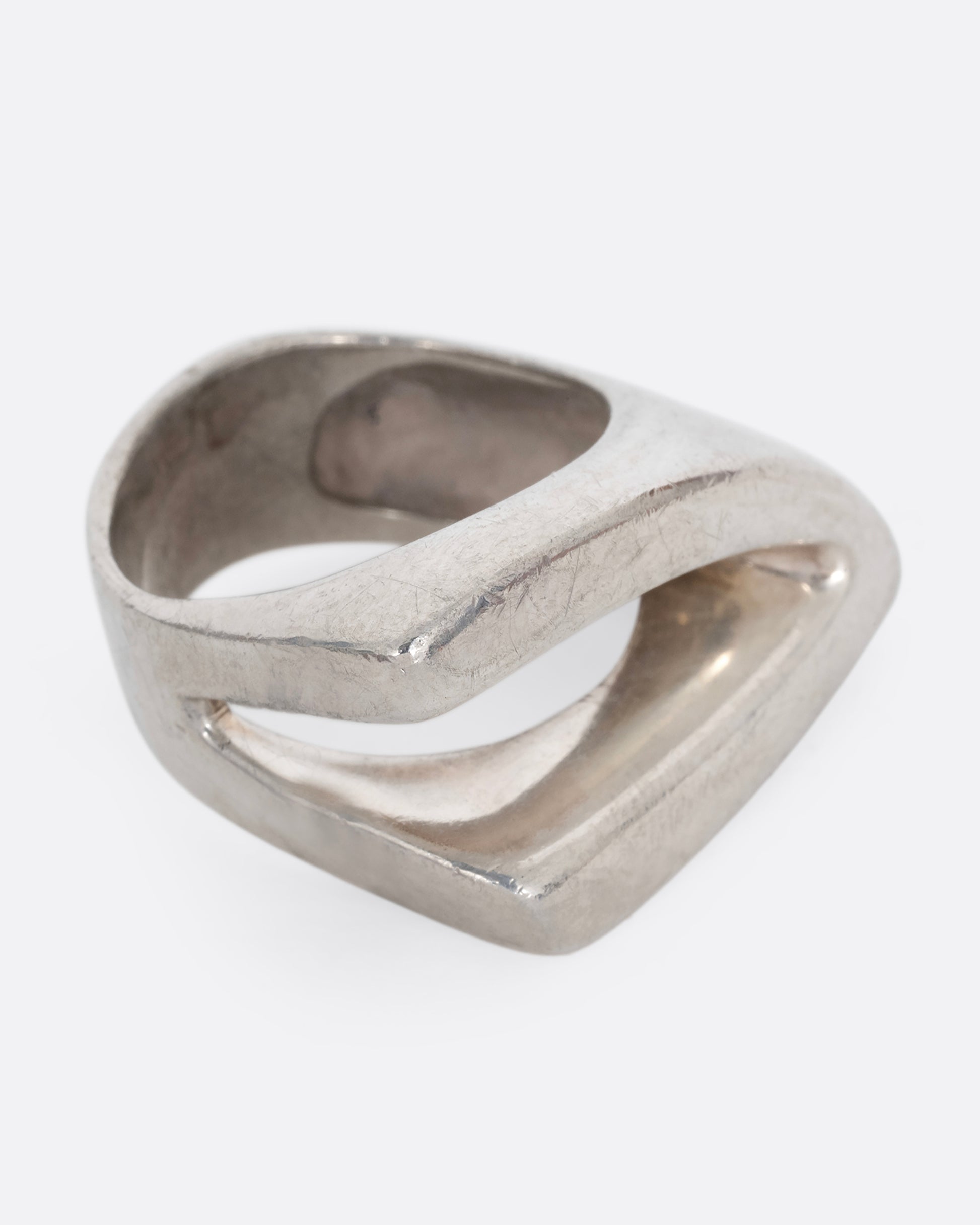 A silver ring with an angular cutout, shown from the side.