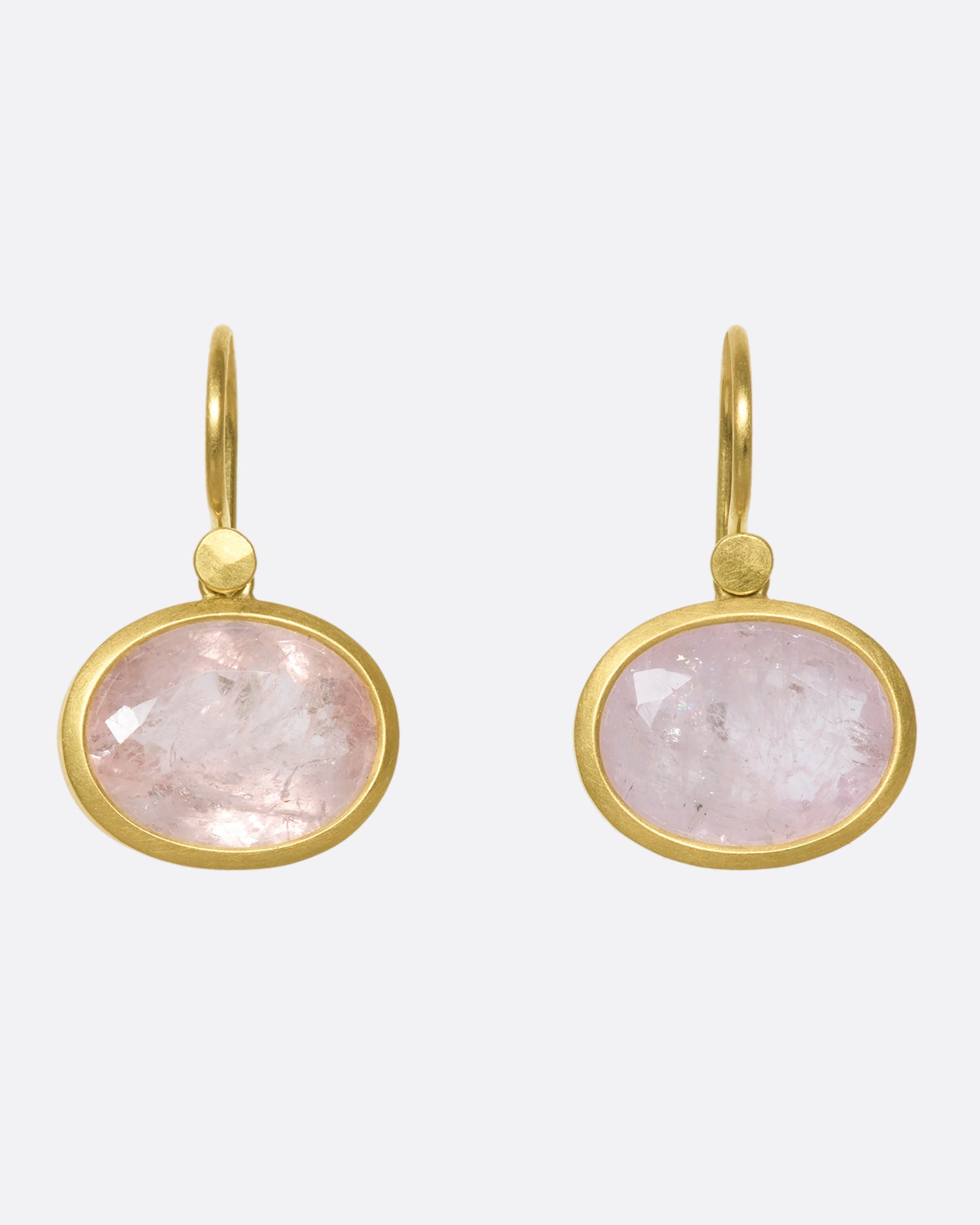 A pair of oval morganite drop earrings with yellow gold bezels and hooks.