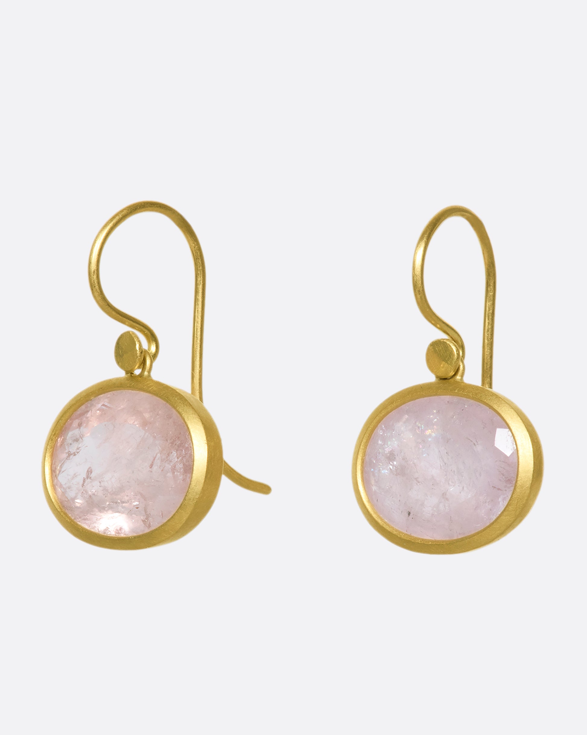 A side view of a pair of oval morganite drop earrings with yellow gold bezels and hooks.