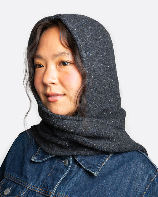 A donegal flecked charcoal hooded scarf with elongated sides, shown wrapped on a person.