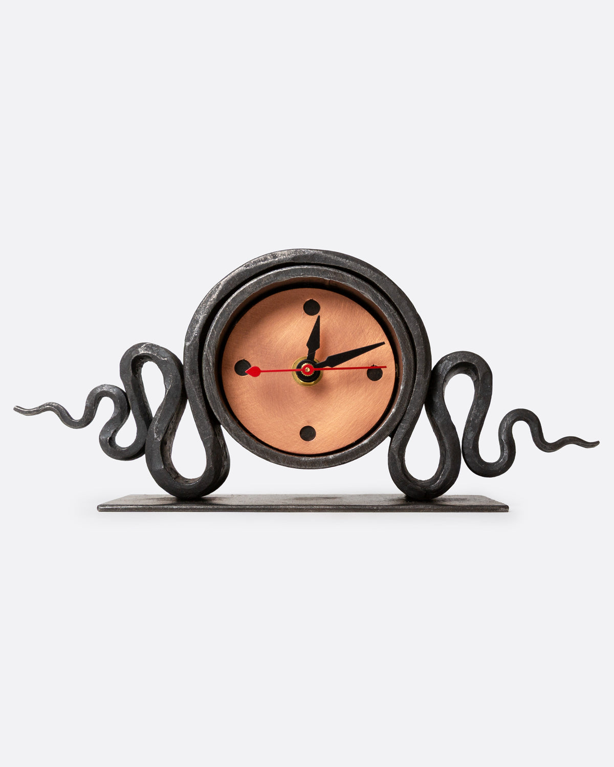 An iron clock with a bright copper face and a writhing snake, shown from the front.