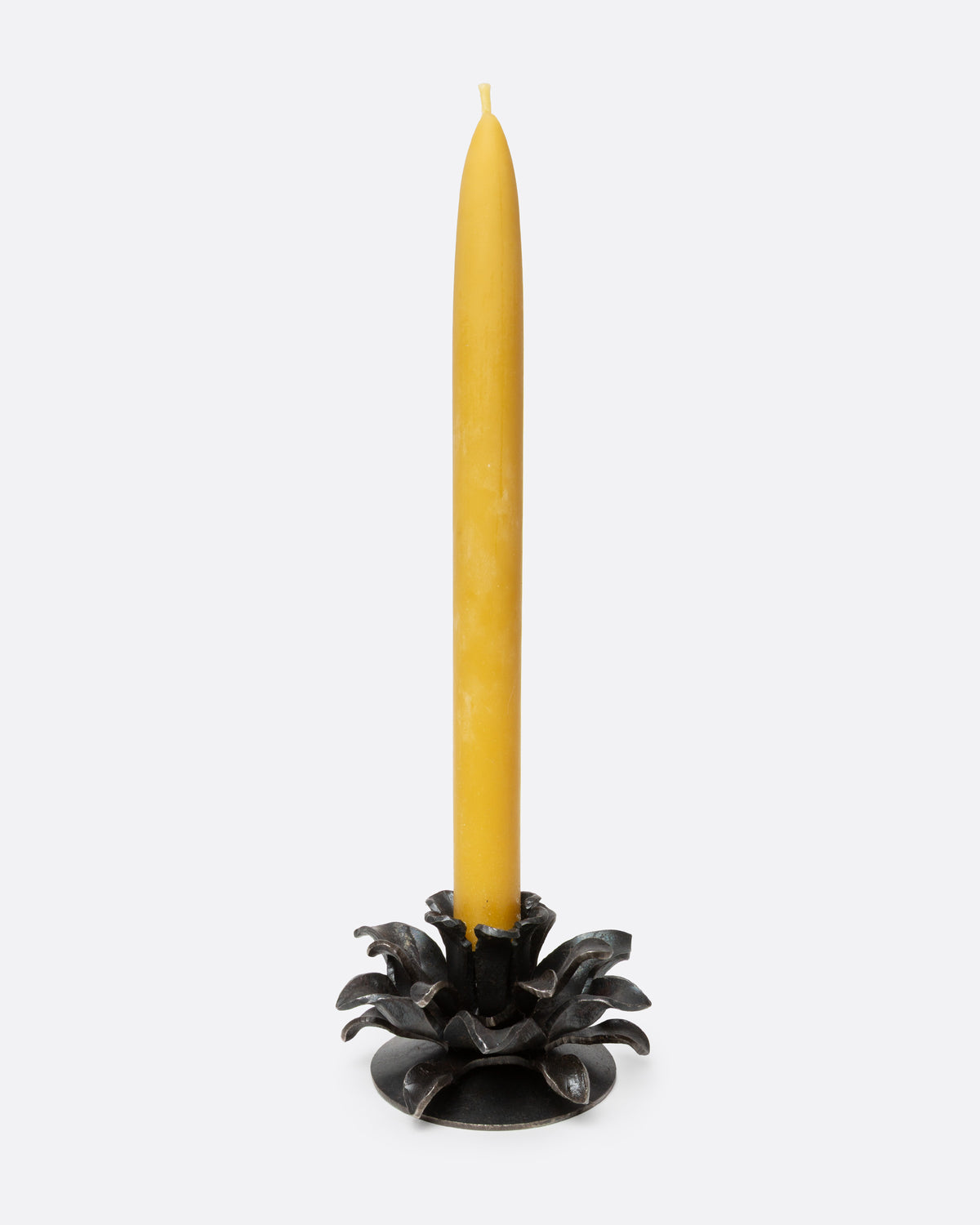 An iron candle holder shaped like stylized flower, shown from the front with a candle in it.
