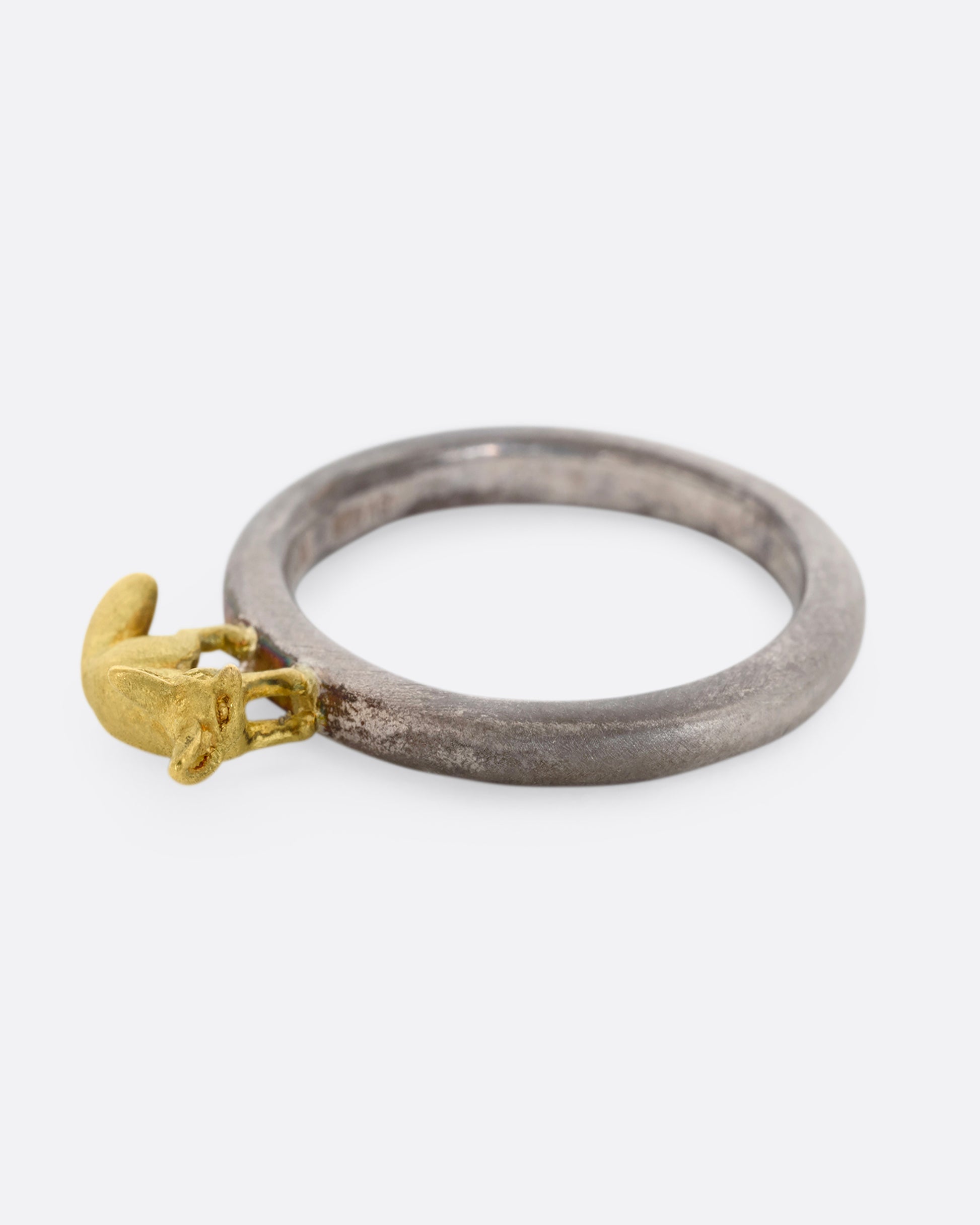 A sterling silver ring with a yellow gold fennec fox standing on the band. Shown laying flat.