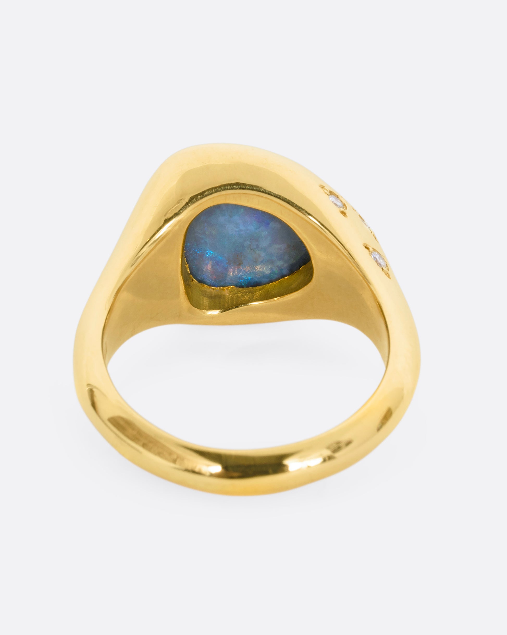 A trillion cut opal in a yellow gold setting with white diamonds on the shoulders. View from the back.