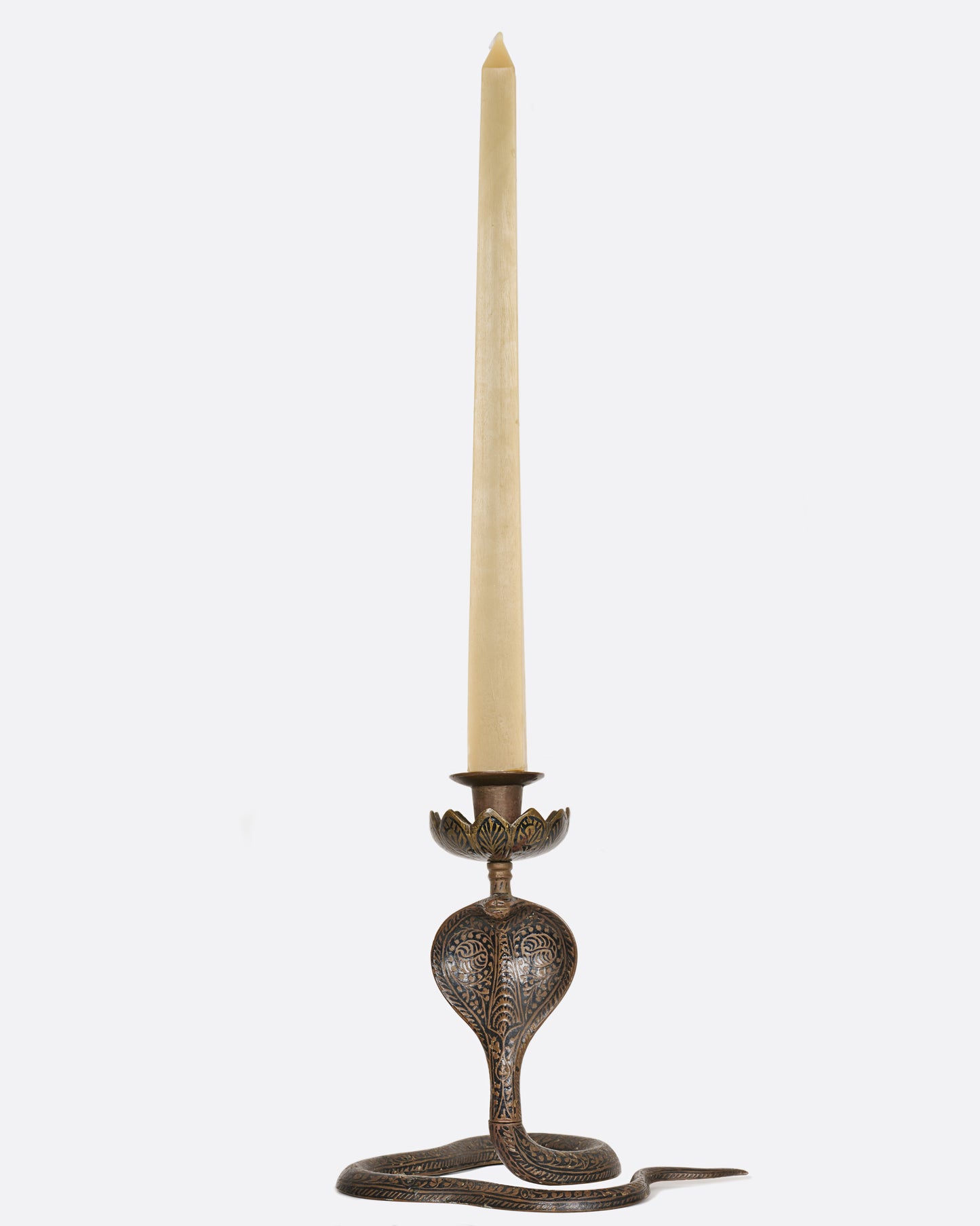 A brass and niello candle holder. View from the front with a candle.