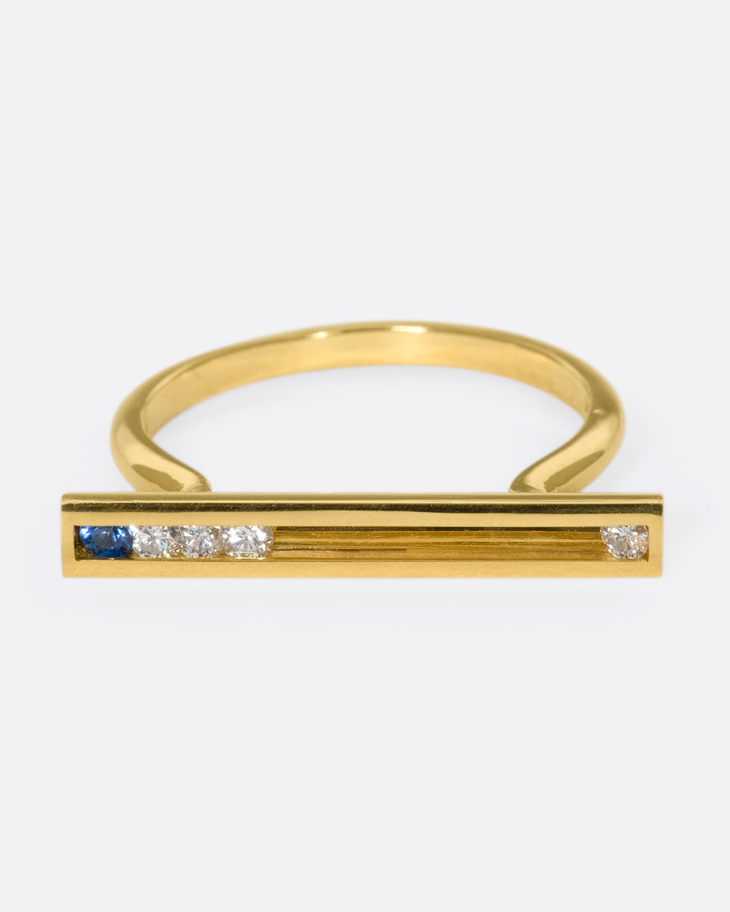 A flat-face ring with blue sapphires and diamonds that glide across an 18K gold bar.