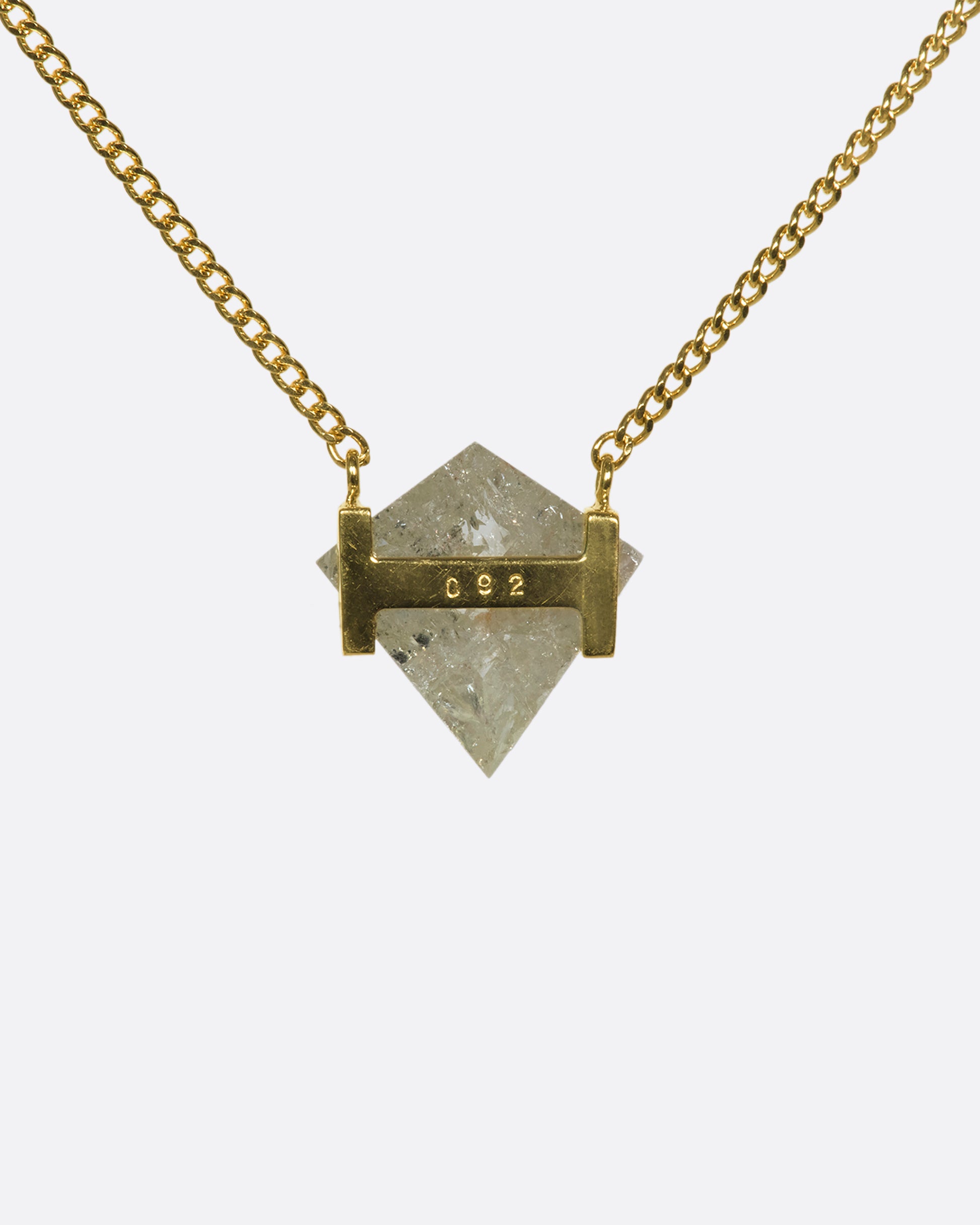 A shield-shaped icy gray diamond suspended between two 18k gold squares