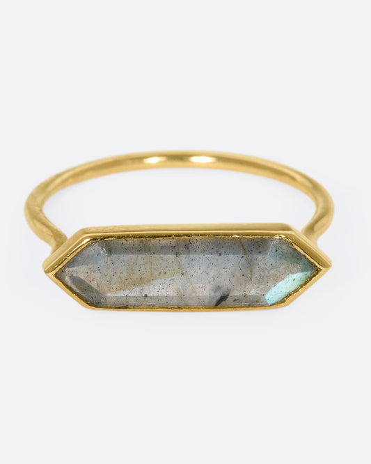 A yellow gold ring with a hexagonal labradorite bar, shown from the front. 