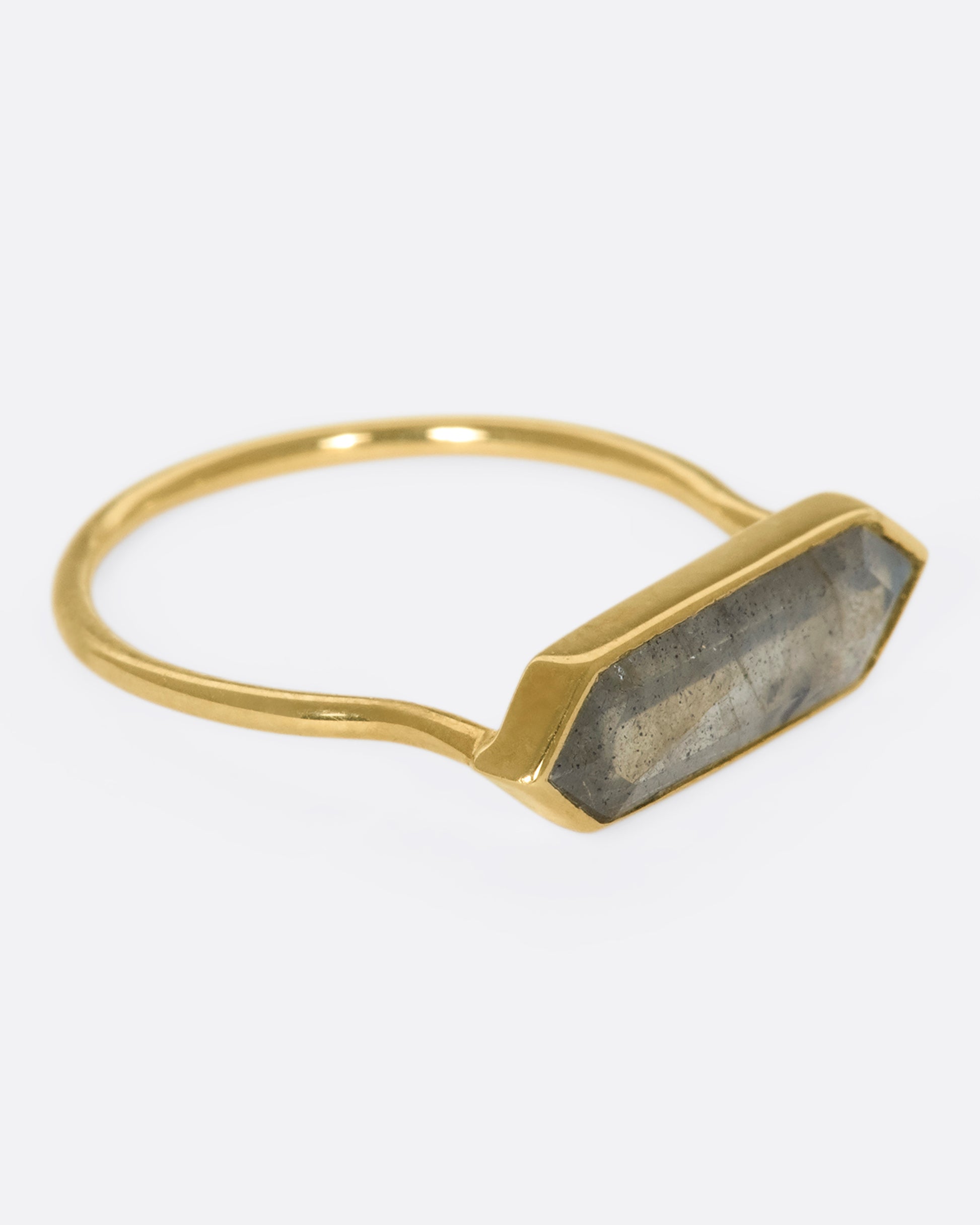 A yellow gold ring with a hexagonal labradorite bar, shown from the side.