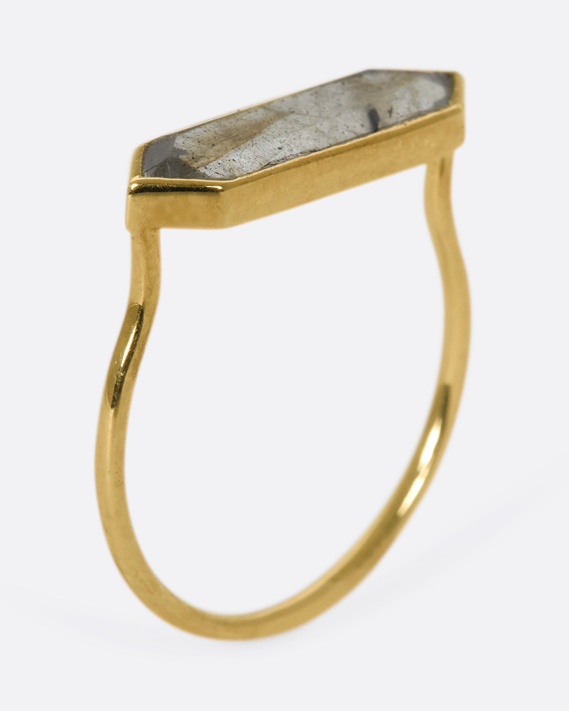 A yellow gold ring with a hexagonal labradorite bar, shown from the side, standing up.