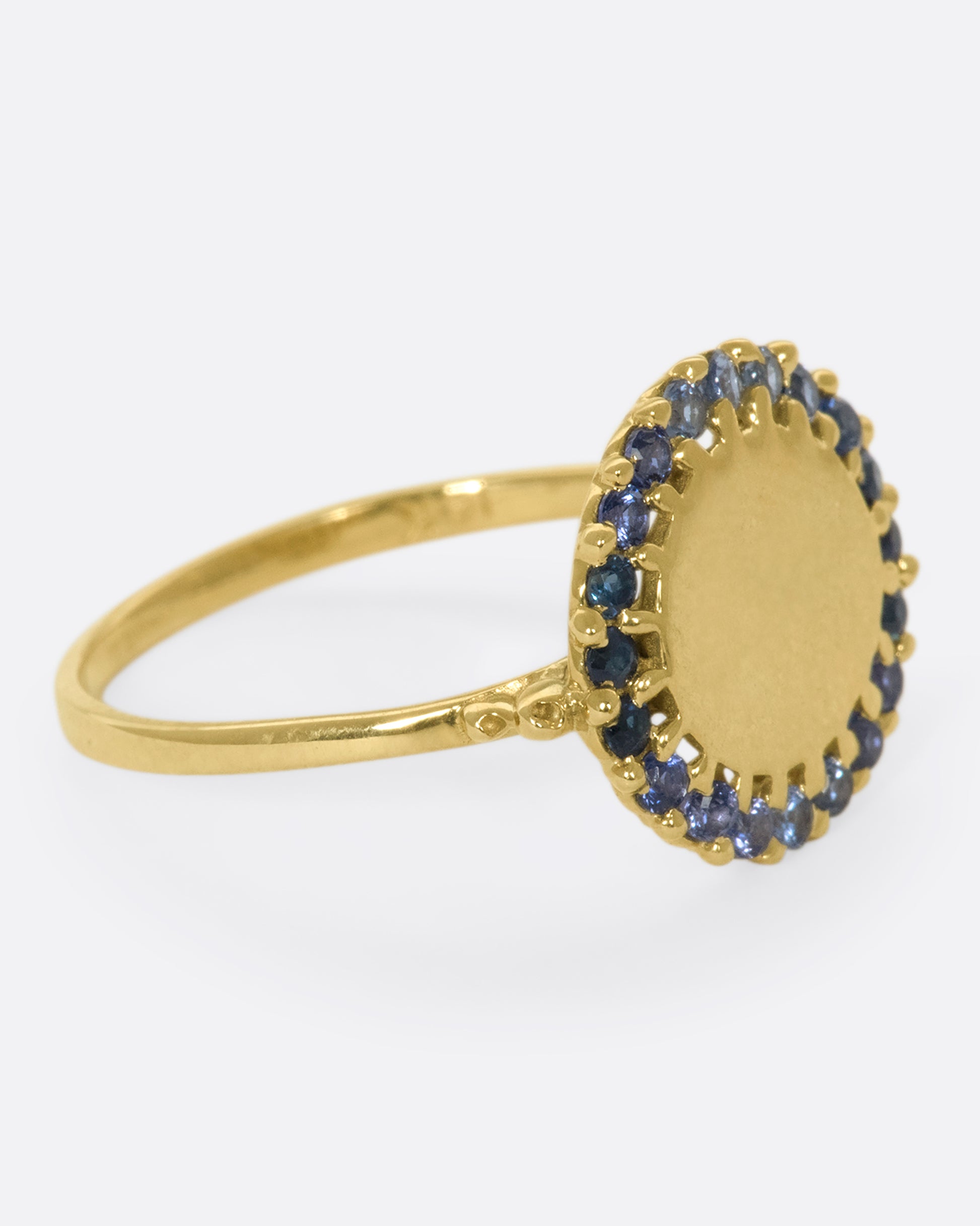 A 14k gold circle ring with a halo of ombré blue sapphires