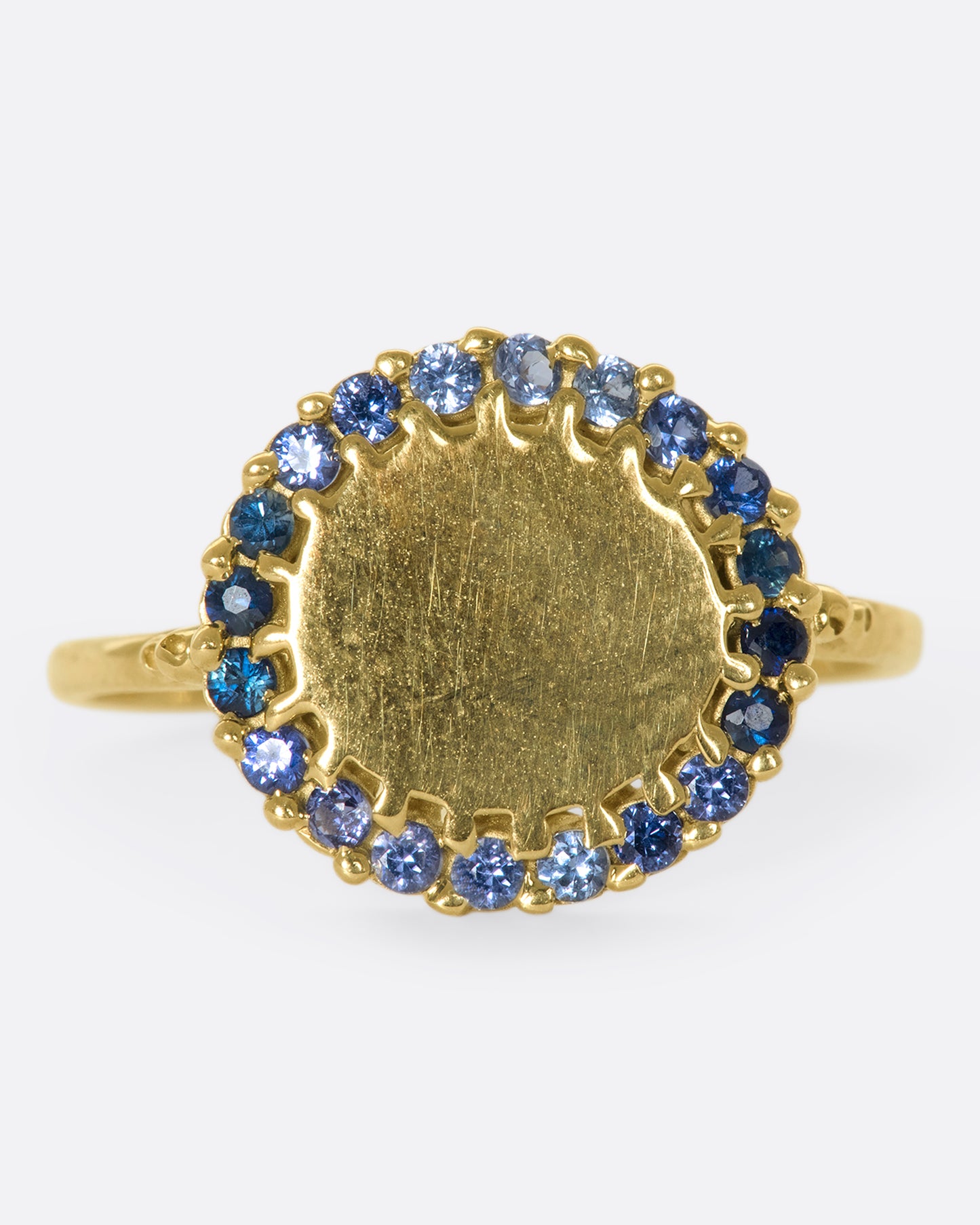 A 14k gold circle ring with a halo of ombré blue sapphires