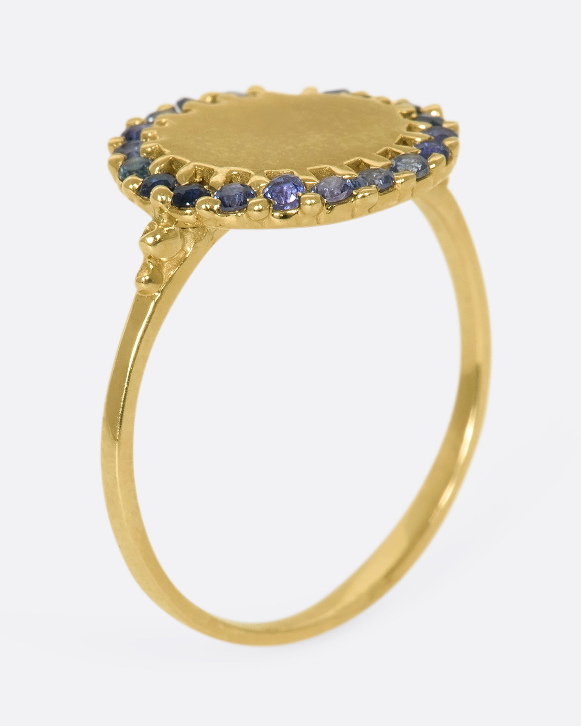 A 14k gold circle ring with a halo of ombré blue sapphires