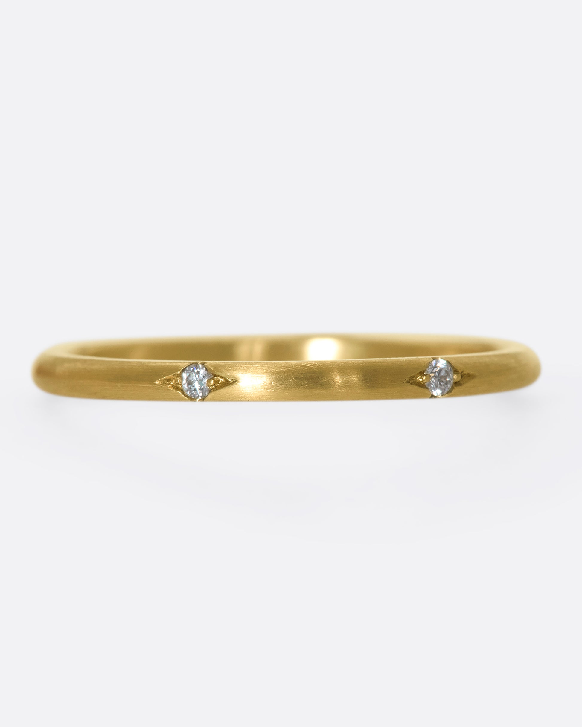 This 10k gold stacking ring features two flush-set white diamonds that sink into the soft gold band