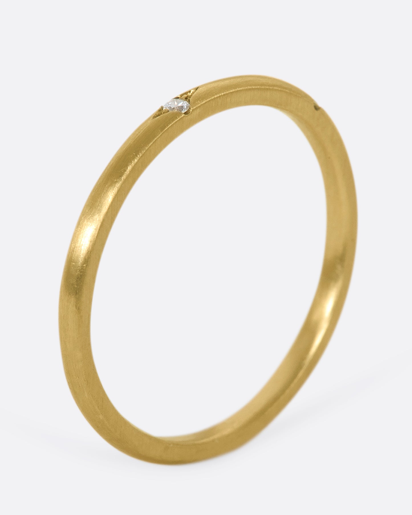 This 10k gold stacking ring features two flush-set white diamonds that sink into the soft gold band