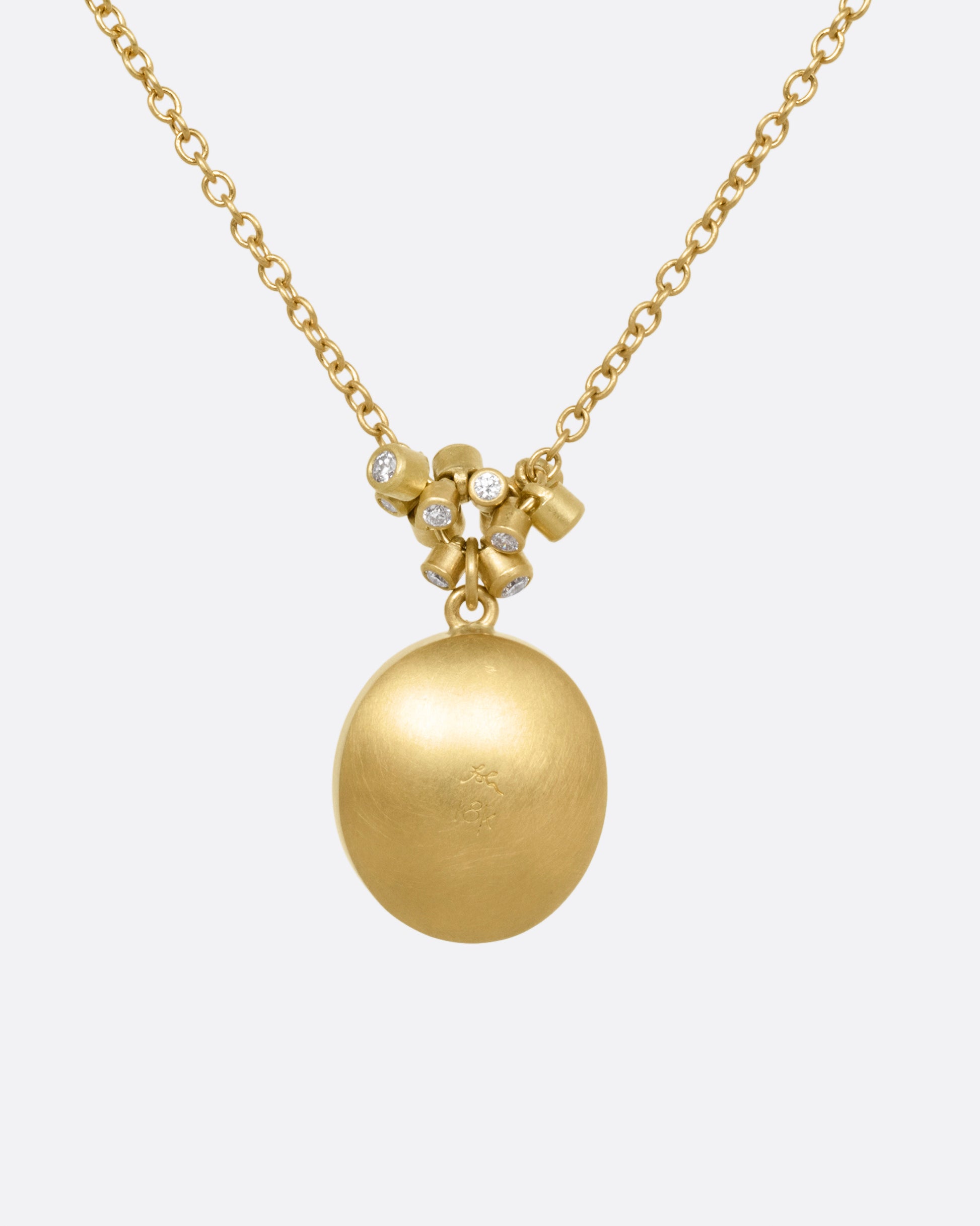 A yellow gold pendant necklace with a amethyst with a hand carved strawberry and a cluster of diamond charms, shown from the back.