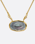 A yellow gold necklace with an eye intaglio in a bezel set clear quartz, set with a slice of abalone behind. Diamond anemones accent the fine cable chain. Shown from the front.