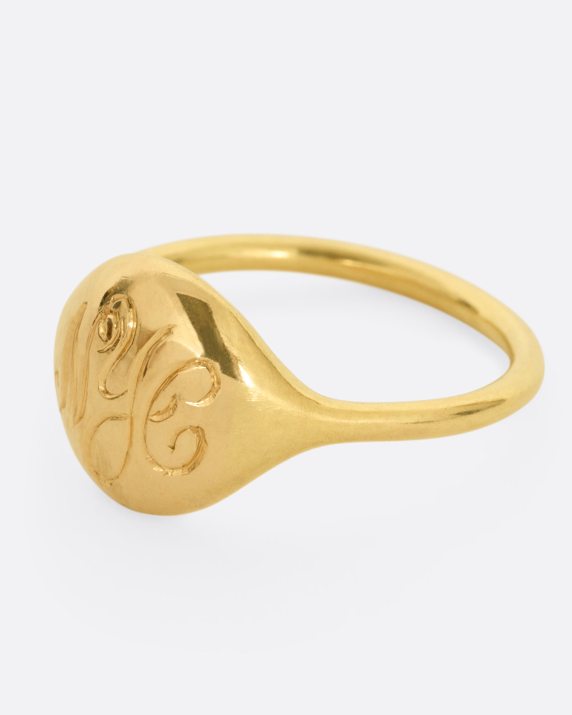 A yellow gold ring with NYC in cursive script. Shown from the side.
