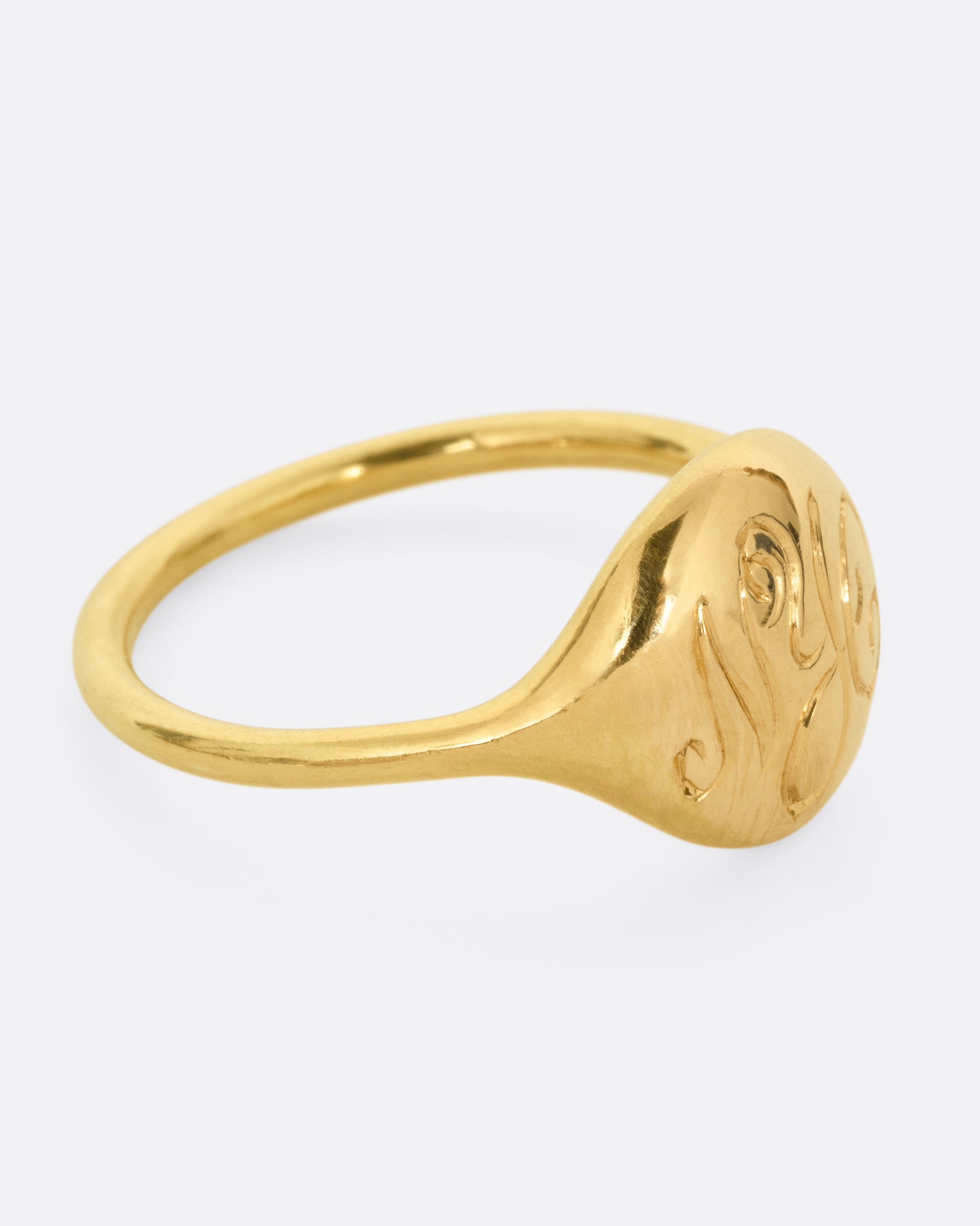 A yellow gold ring with NYC in cursive script. Shown from the side.