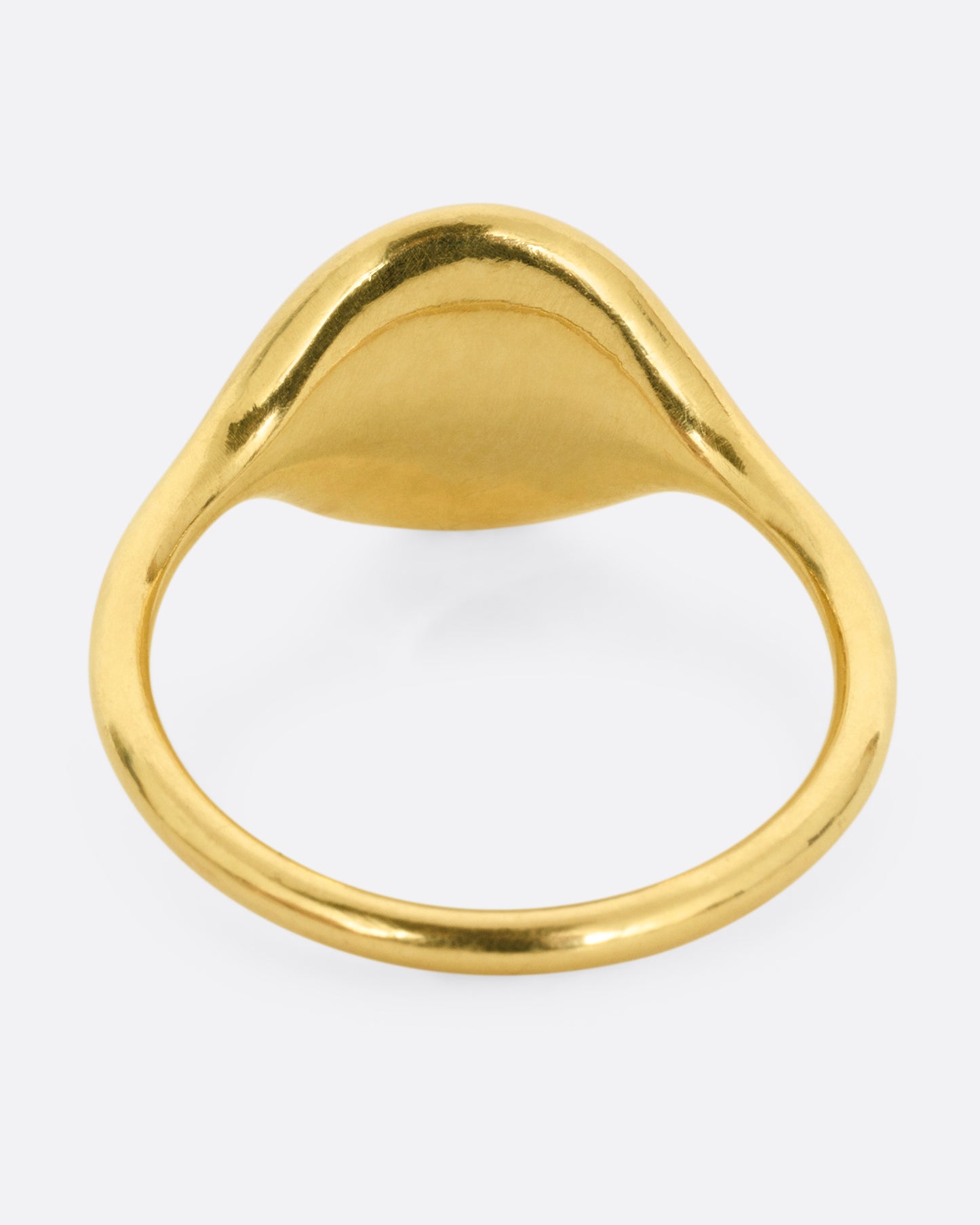A yellow gold ring with NYC in cursive script. Shown from the back.
