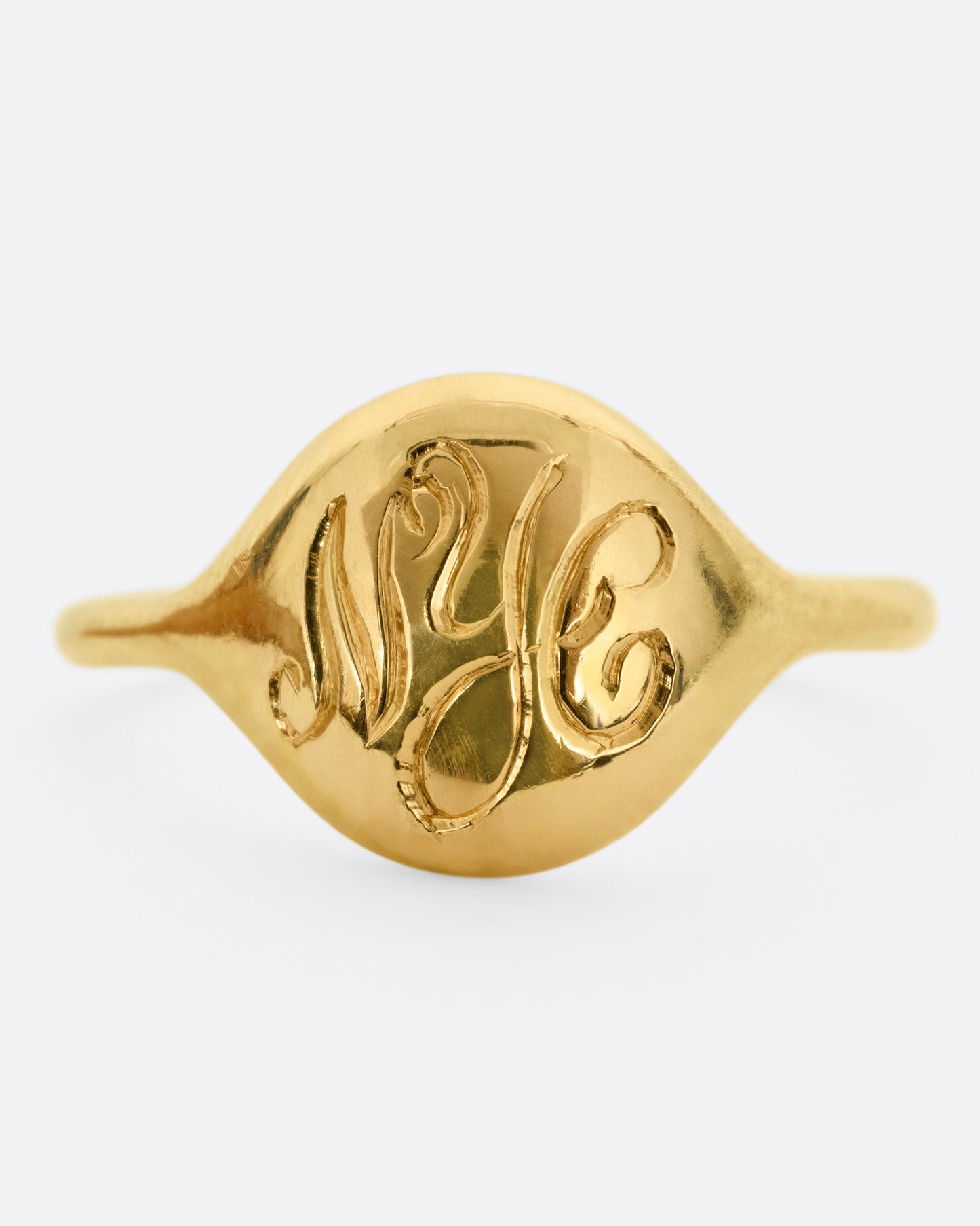 A yellow gold ring with NYC in cursive script. Shown from the front.