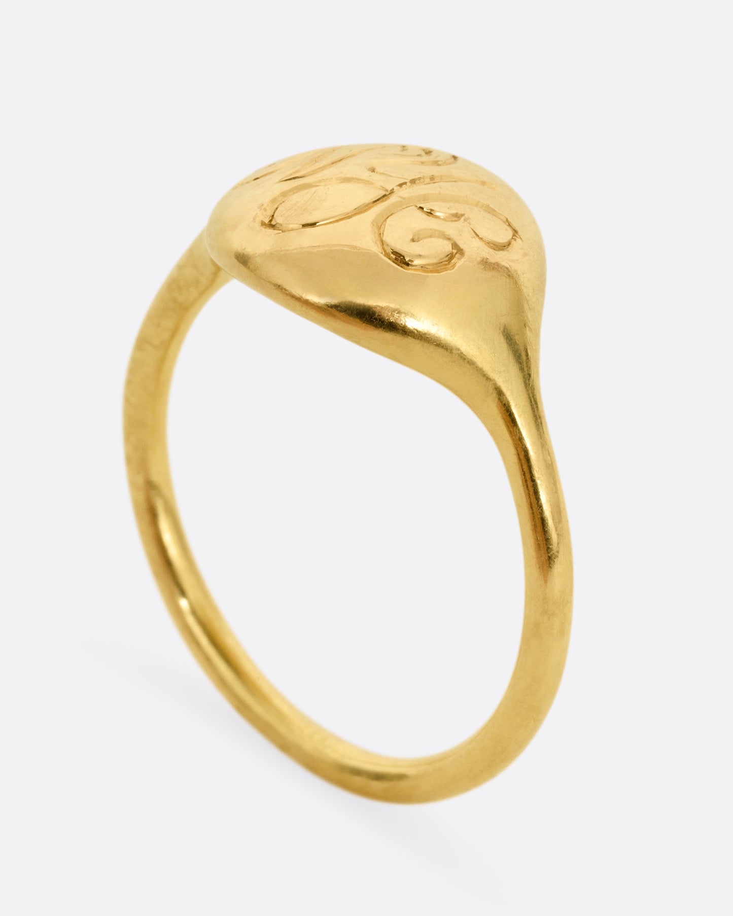 A yellow gold ring with NYC in cursive script. Shown standing up from the side.