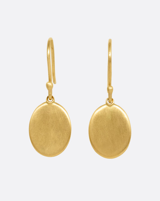 A pair of yellow gold hook earrings with oval dangles, shown from the front.