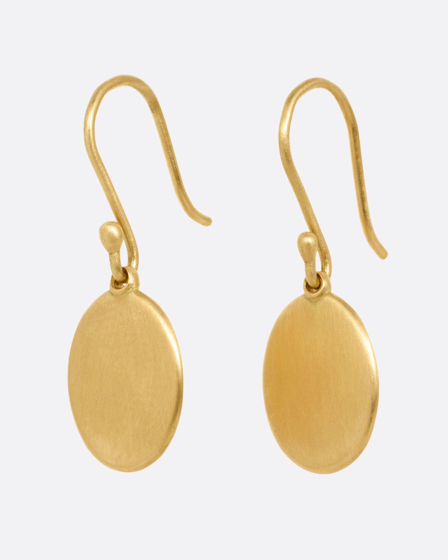 A pair of yellow gold hook earrings with oval dangles, shown from the side.