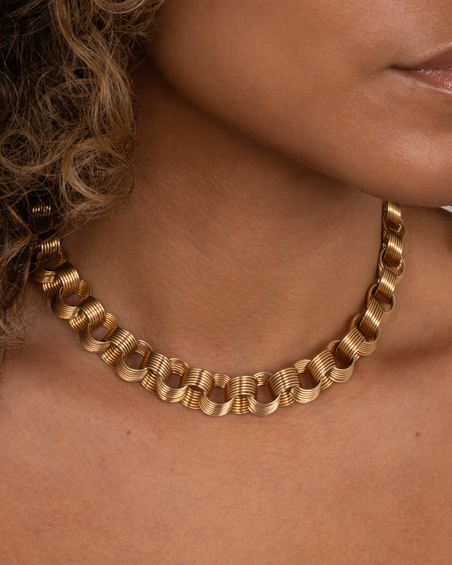 A yellow gold necklace with slanted stacked hoop links, shown worn.