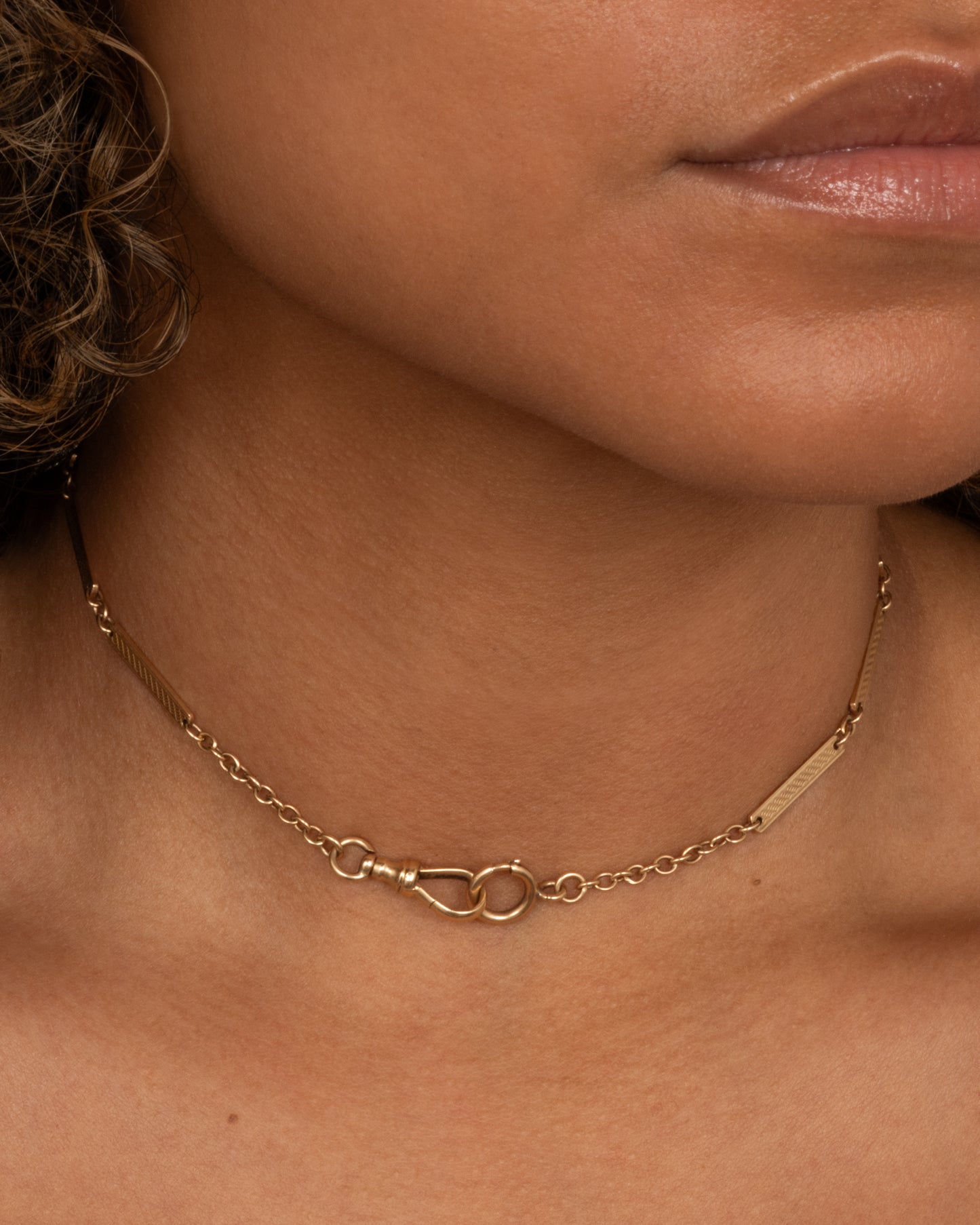 A yellow gold watch chain with textured elongated bar links. shown worn.