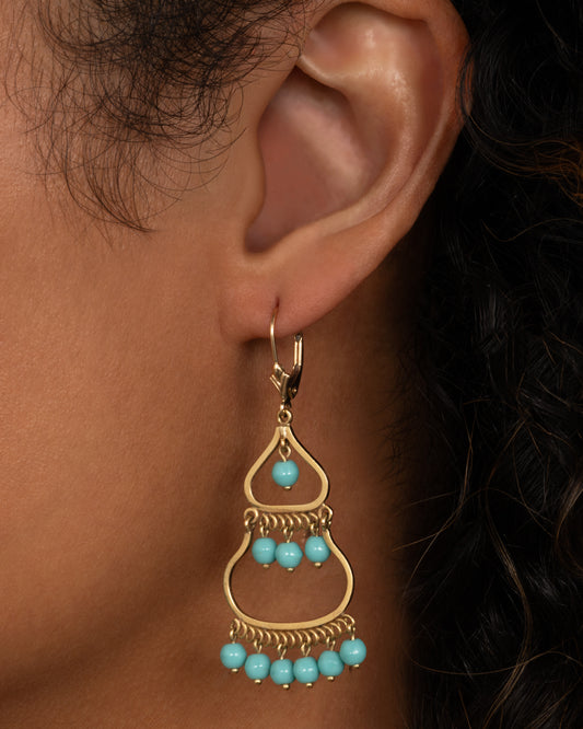 A pair of yellow gold  drop chandelier earrings with turquoise beads, shown worn.