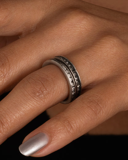 A palladium ring with a queue of diamonds set in a darkened center channel. Shown worn.