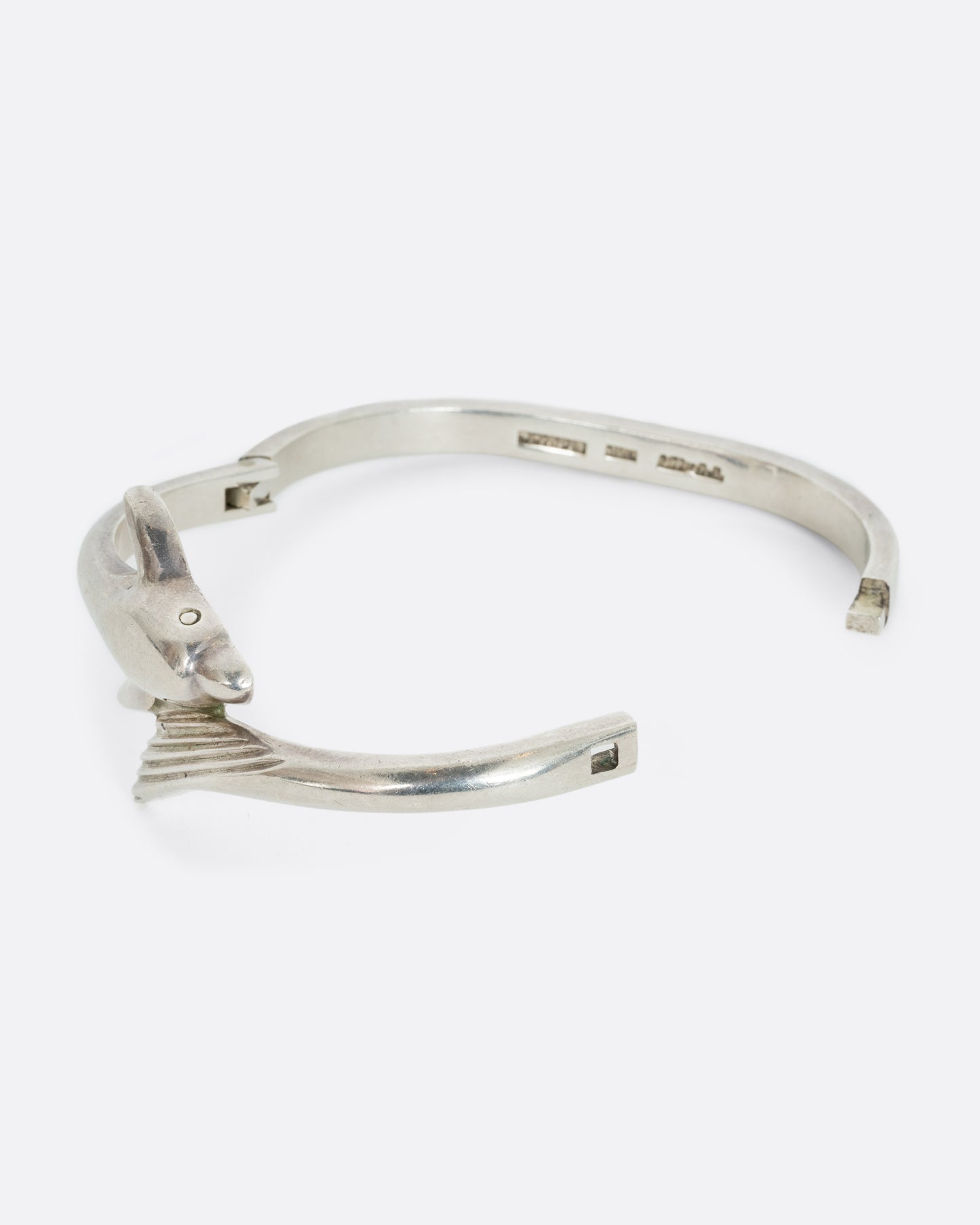 A sterling silver dolphin wrap bracelet. Shown from the side, open.