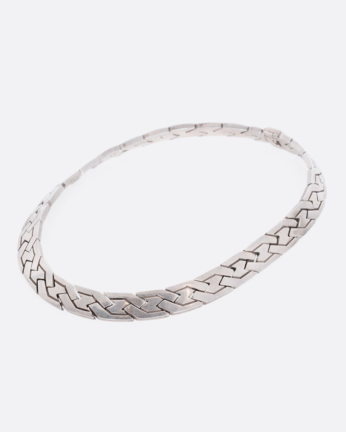 A flat woven link sterling silver necklace. View from the side.