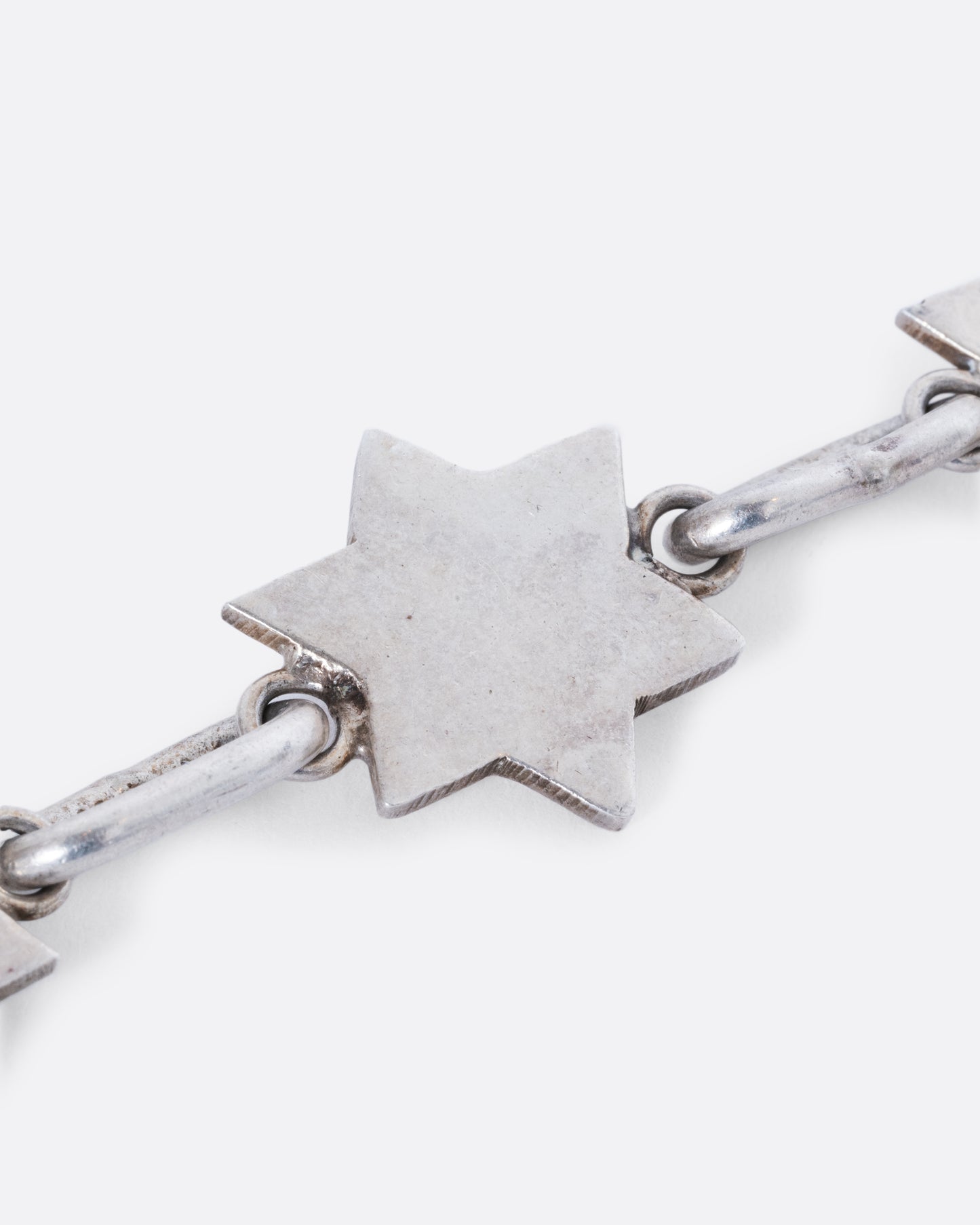 A sterling silver bracelet with star of David links. View of one star link close up.