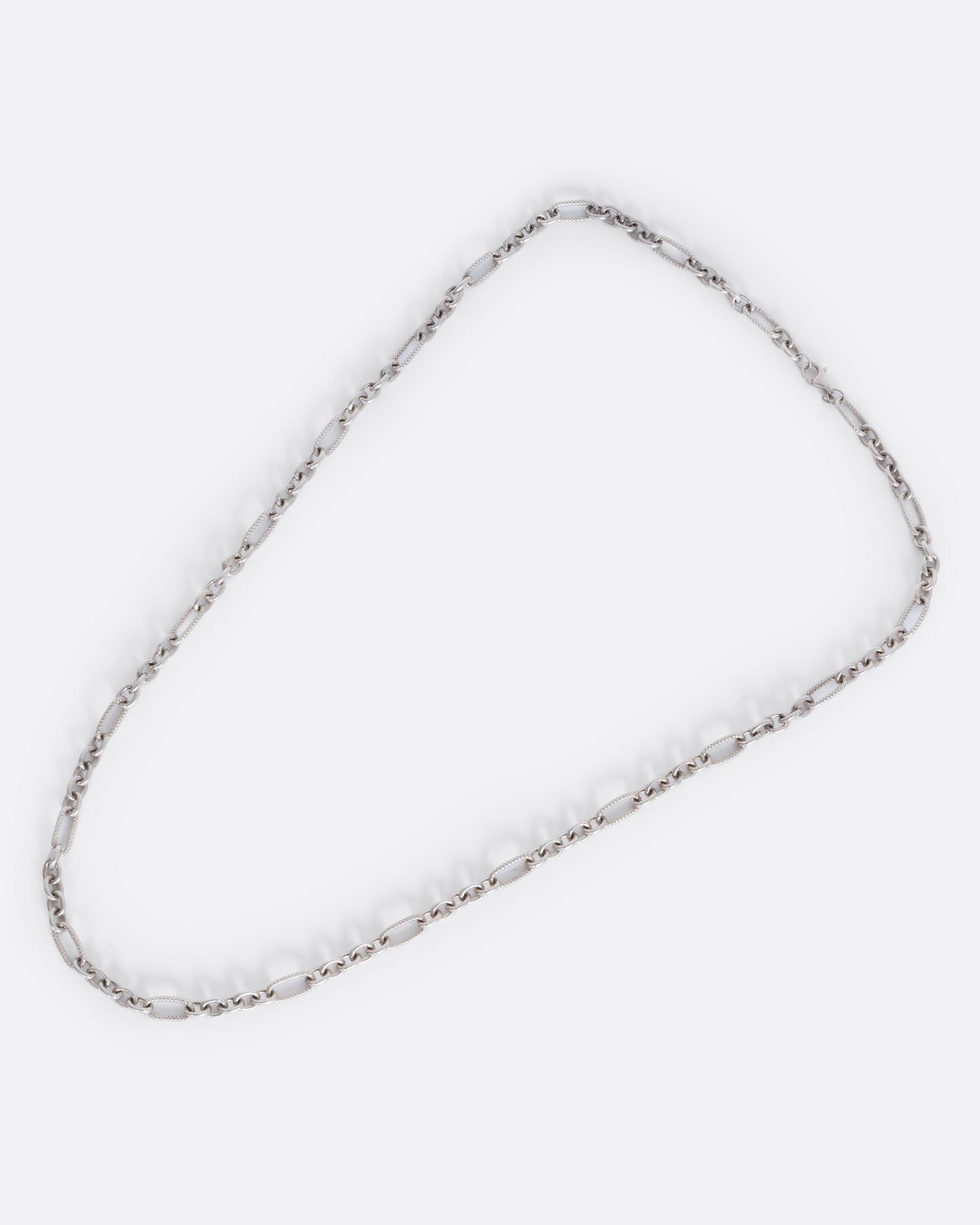 A lengthy textured oval cable chain necklace. View from above of the full necklace.