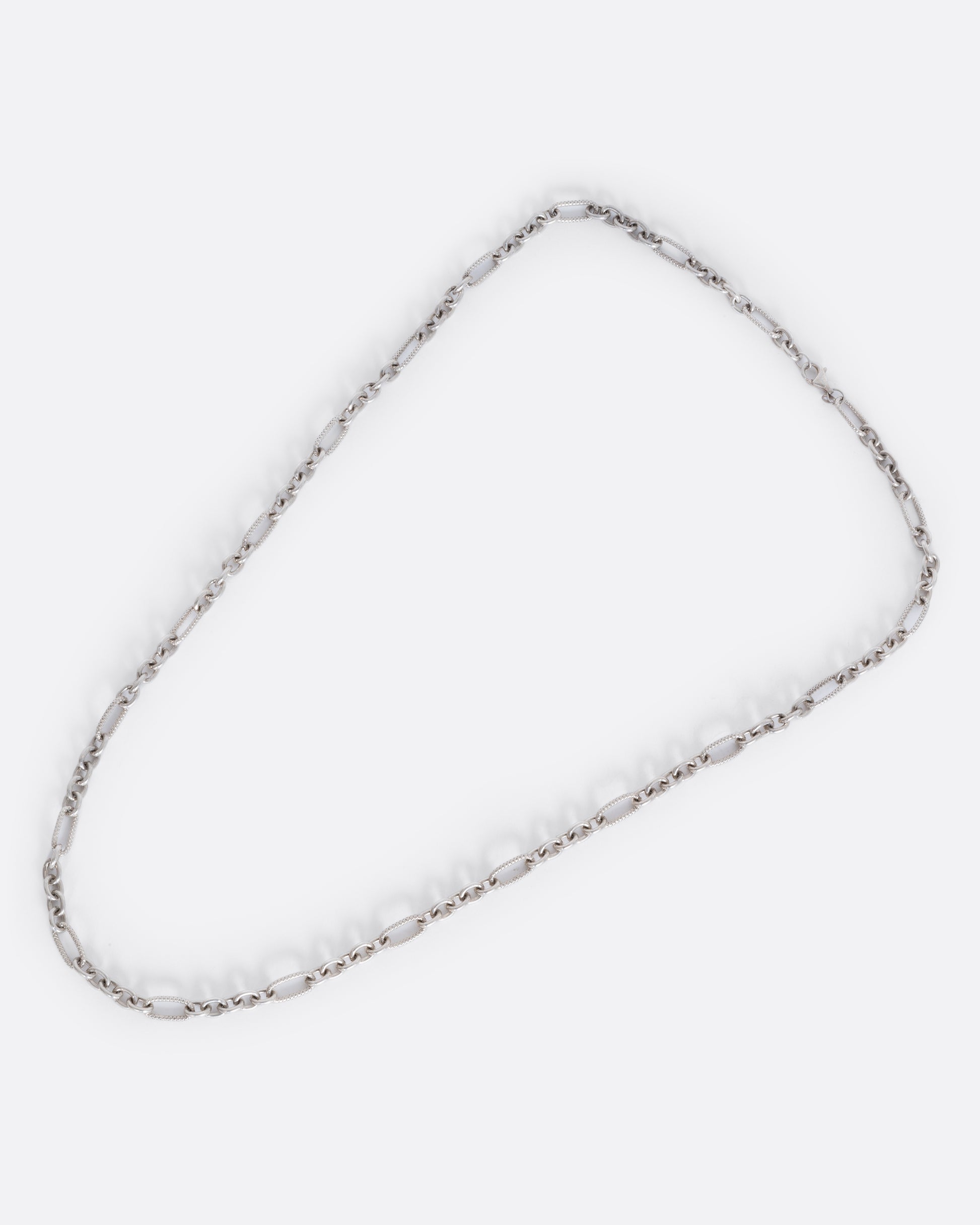 A lengthy textured oval cable chain necklace. View from above of the full necklace.