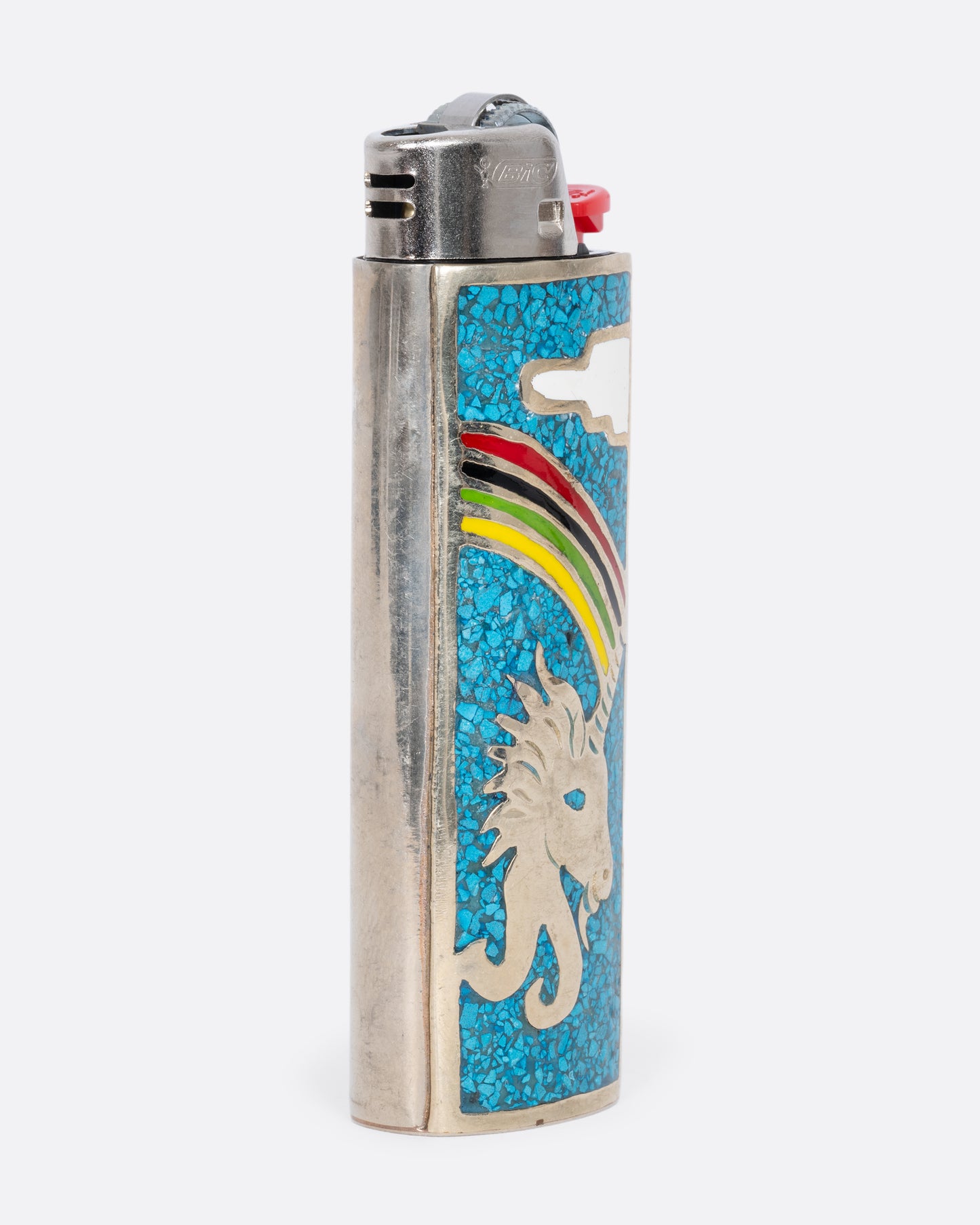 An alpaca silver lighter cover with a unicorn and rainbow. View from the side.