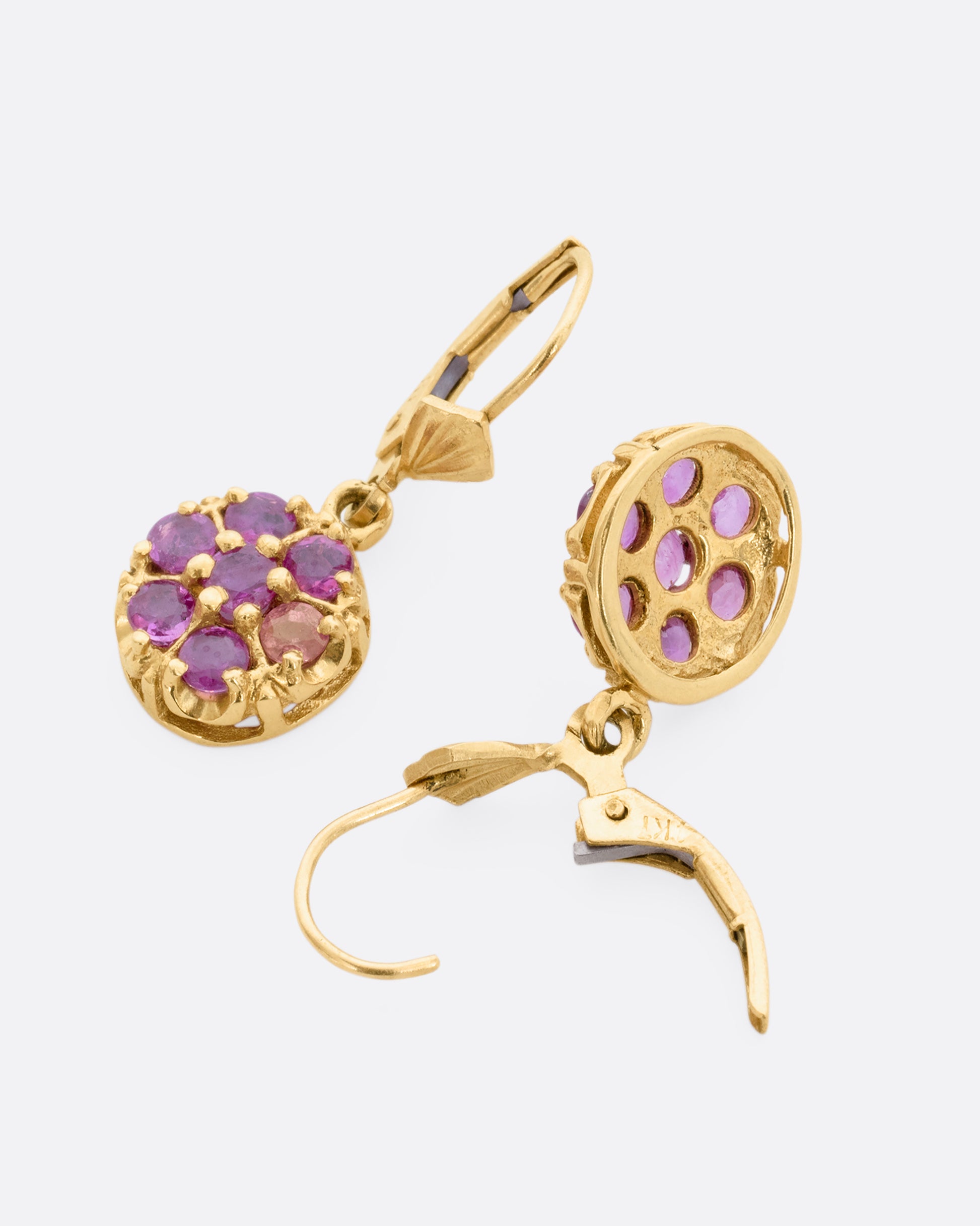 Yellow gold leverback drop earrings with a pink sapphire flower on each. View laying flat.