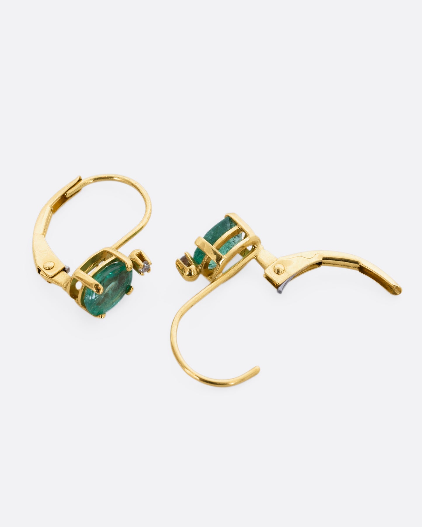 Yellow gold emerald and diamond drop earrings. View laying flat, opened.