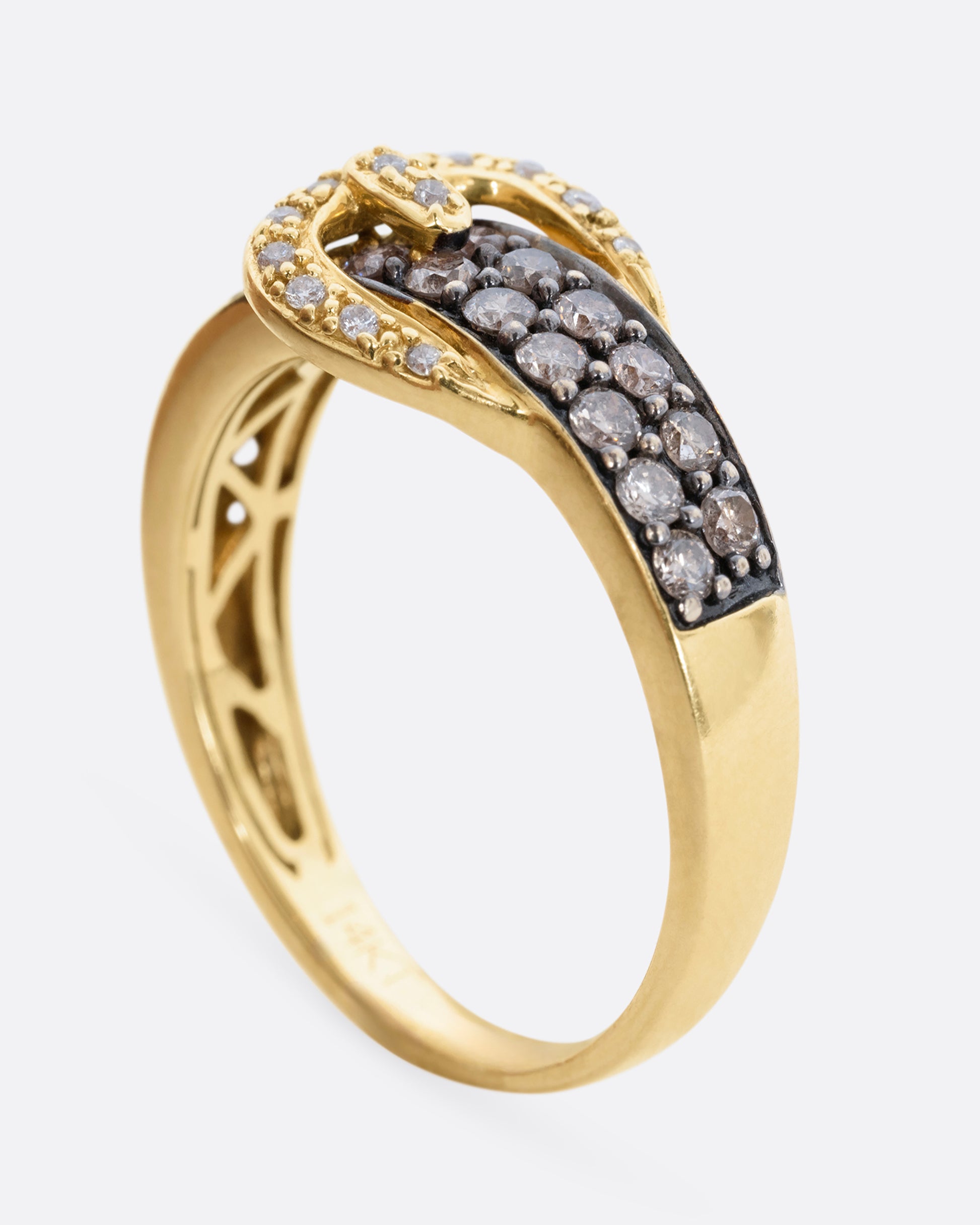 A diamond encrusted black and yellow gold belt buckle ring. View from the side, standing up.