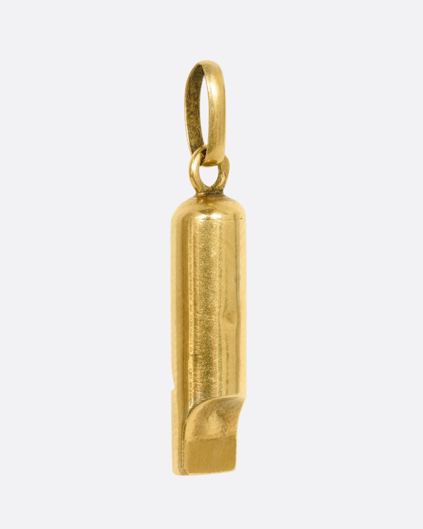 A yellow old whistle charm. View from the back.