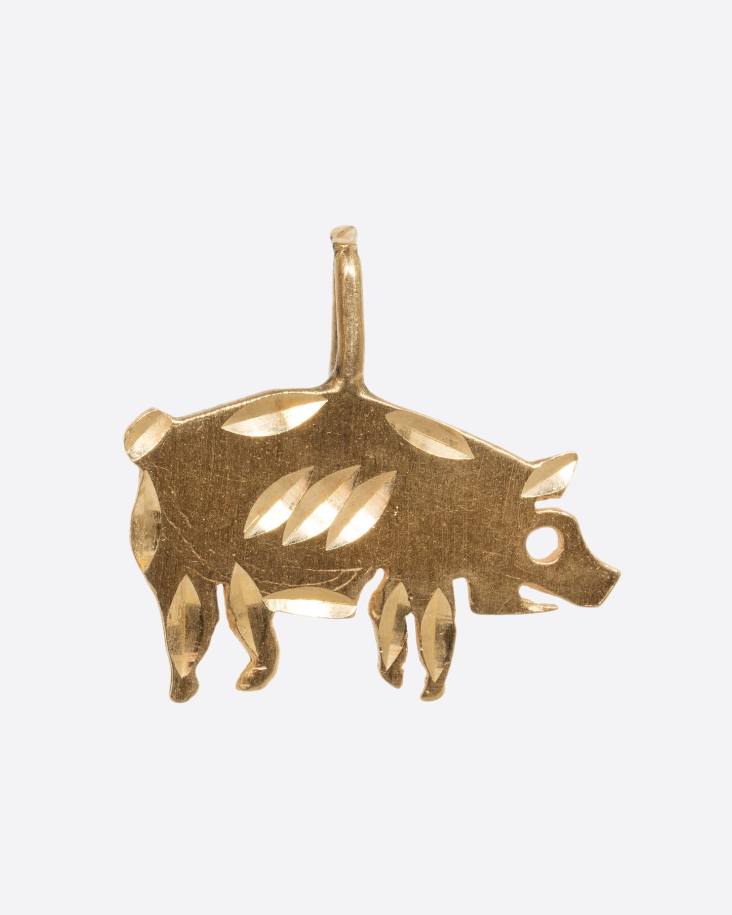 A yellow gold etched pig charm. View from the front.