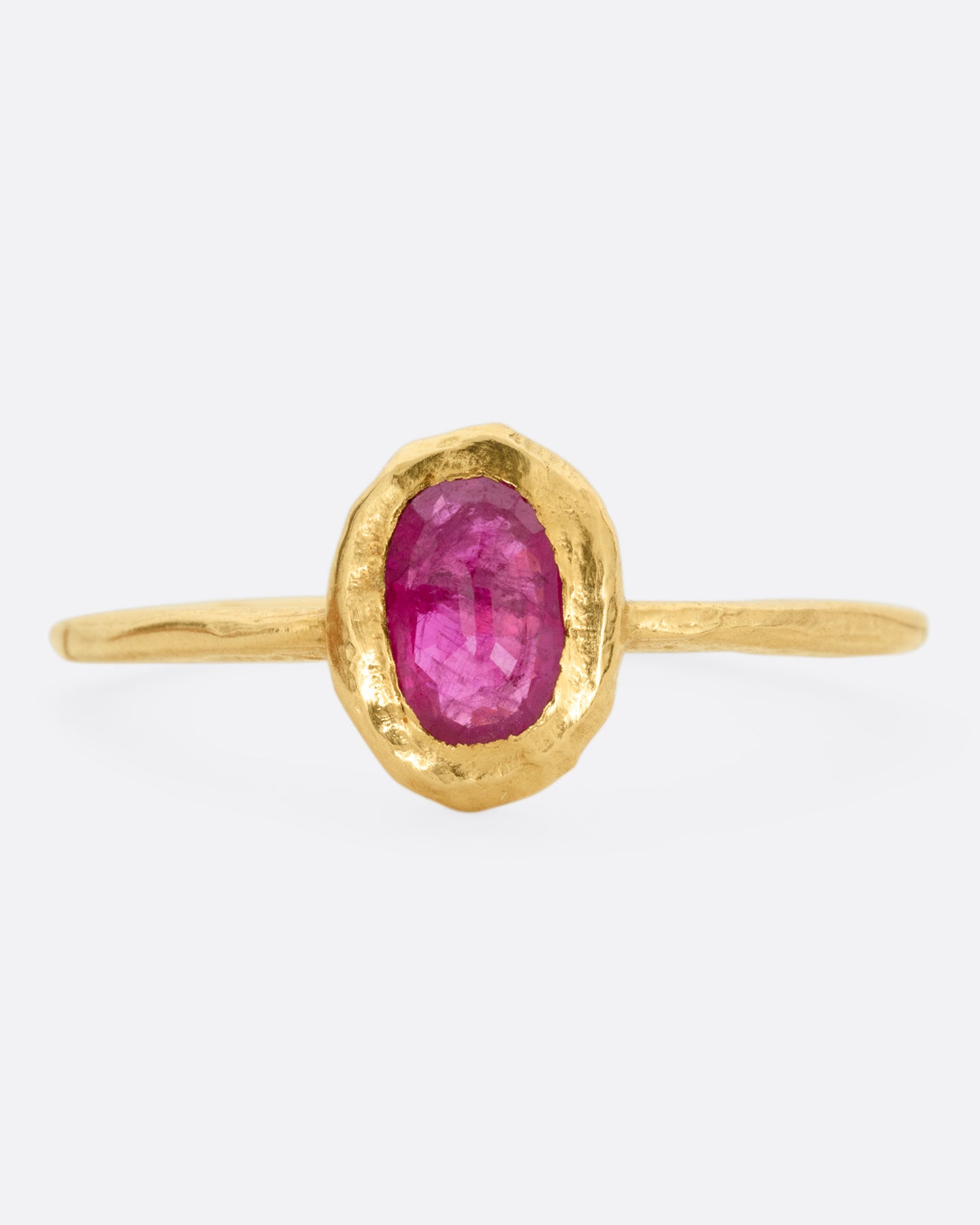 A yellow gold ring with a bezel set ruby, shown from the front.